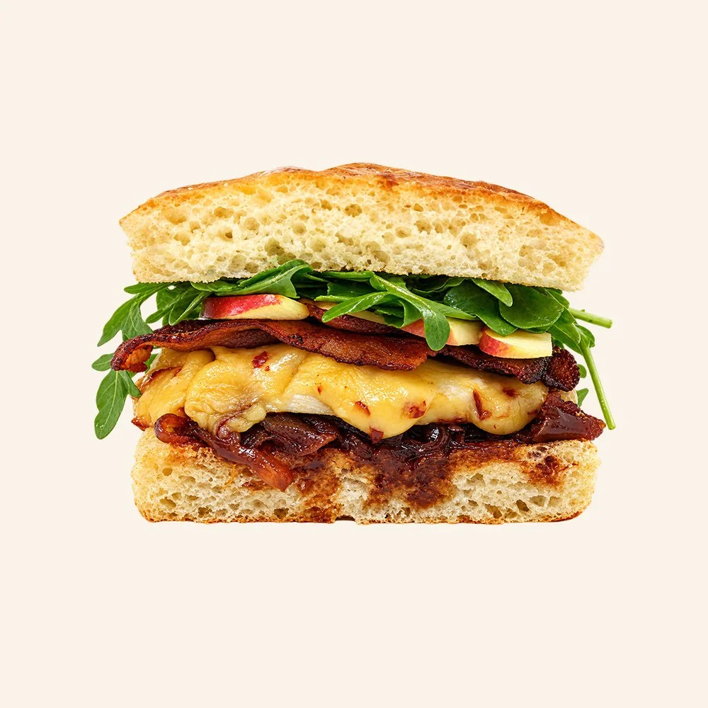 CHICKEN GOUDA - Roasted chicken breast, crispy bacon, onion jam, melted gouda cheese, arugula, Honeycrisp apple, maple vinaigrette on ciabatta bread.
