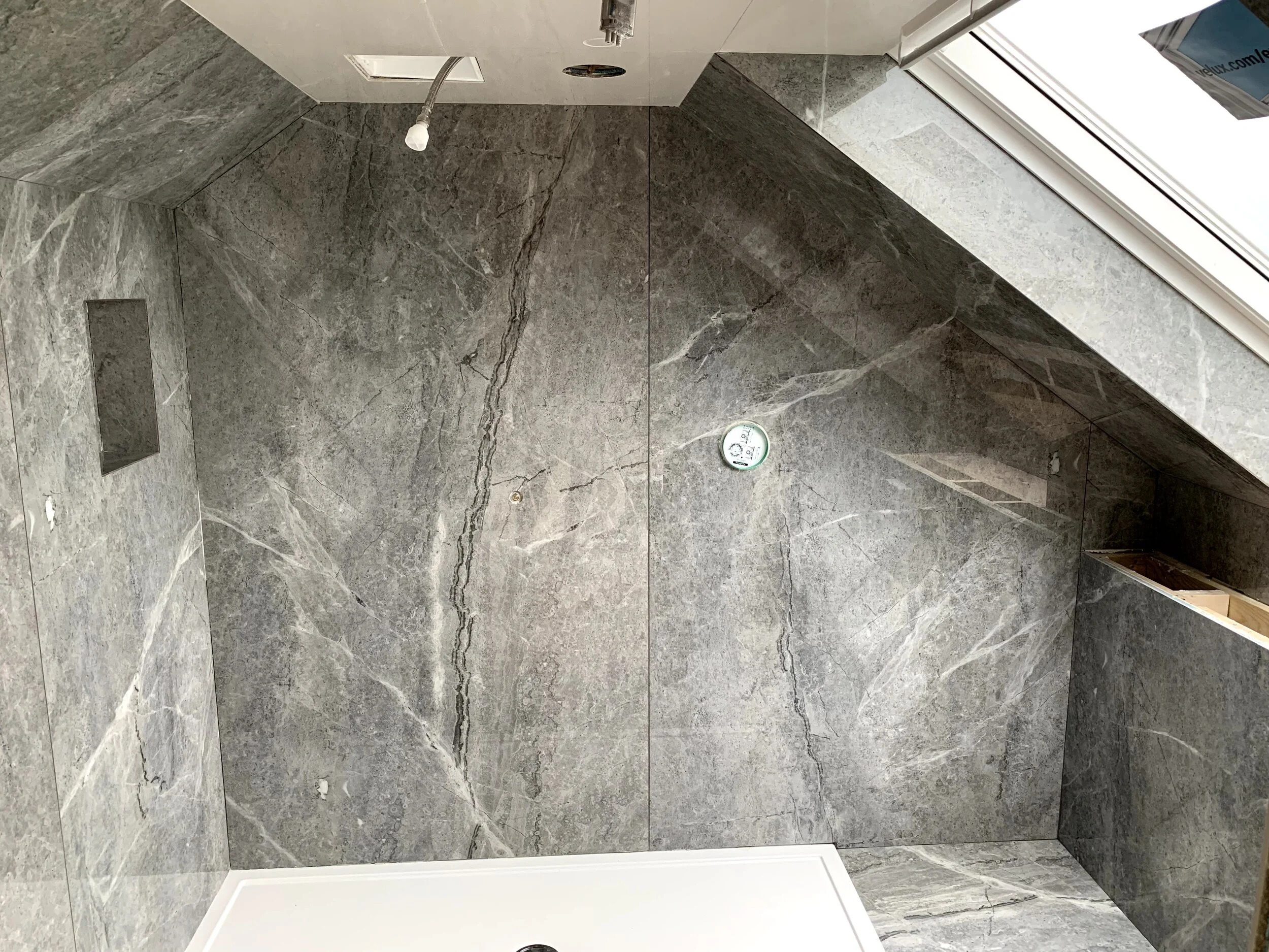 Large format thin Porcelain slabs measuring 2400x1200 used in this converted loft shower room.
