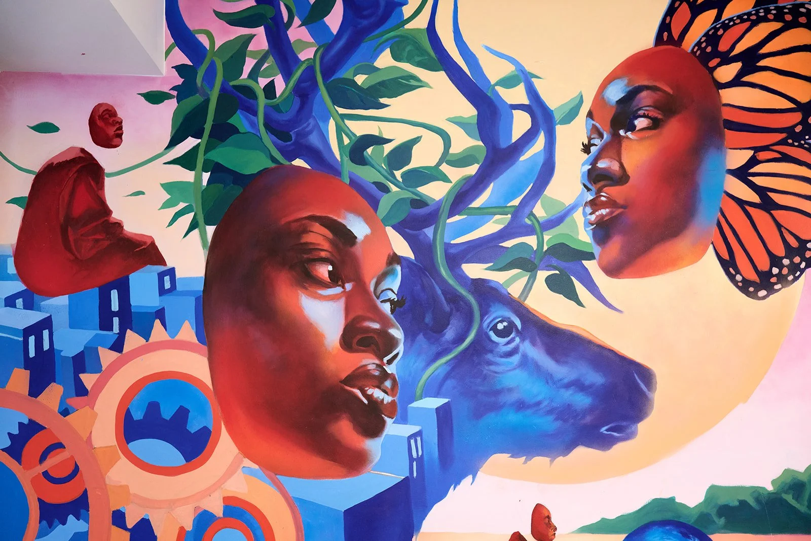 Detail of Aniekan Udofia's mural: two faces, a blue stag and monarch wings