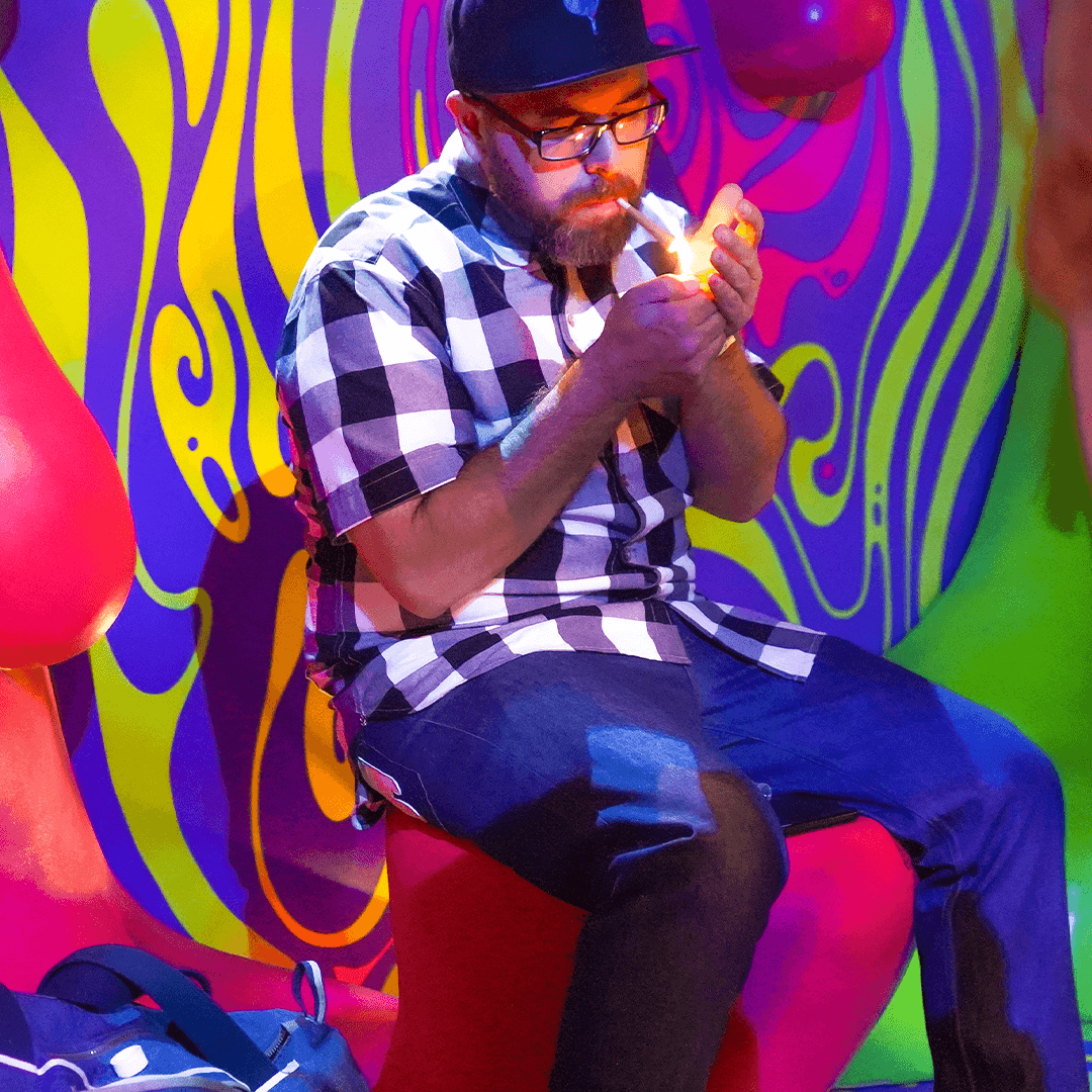 Wonderbrett founder Brett Feldman lighting a joint while seated against a vibrant psychedelic mural. Brett Feldman, founder of the premium California cannabis brand Wonderbrett.