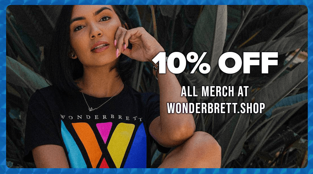 A young woman with shoulder-length black hair, wearing a black Wonder Brett T-shirt with colorful design, sitting outdoors among plants, promoting 10% off all merchandise at wonderbrett.shop.