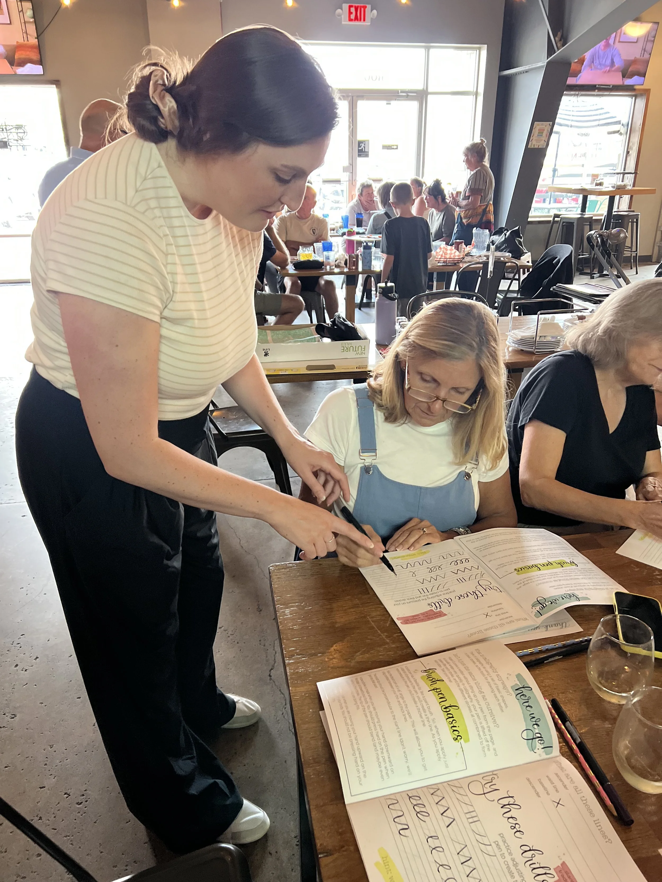 calligraphy instructor assisting a student to hold a brush pen during a calligraphy workshop