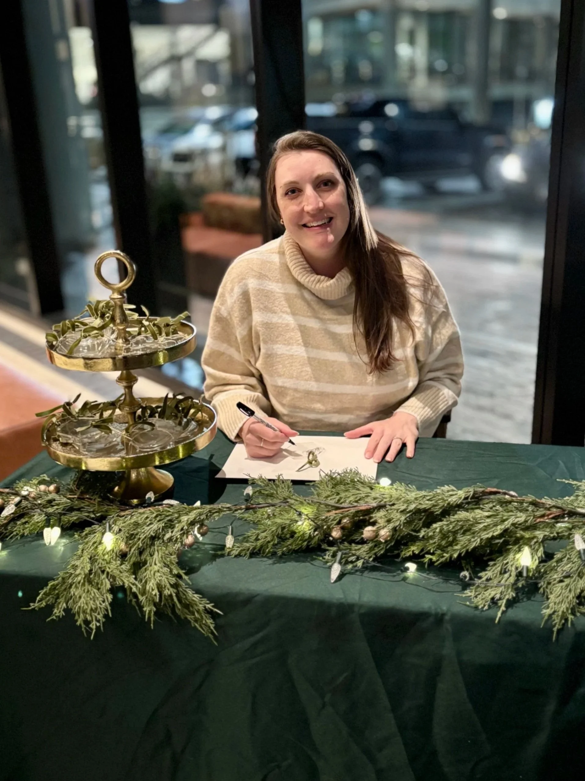 Calligraphy artist seated at a table personalizing ornaments
