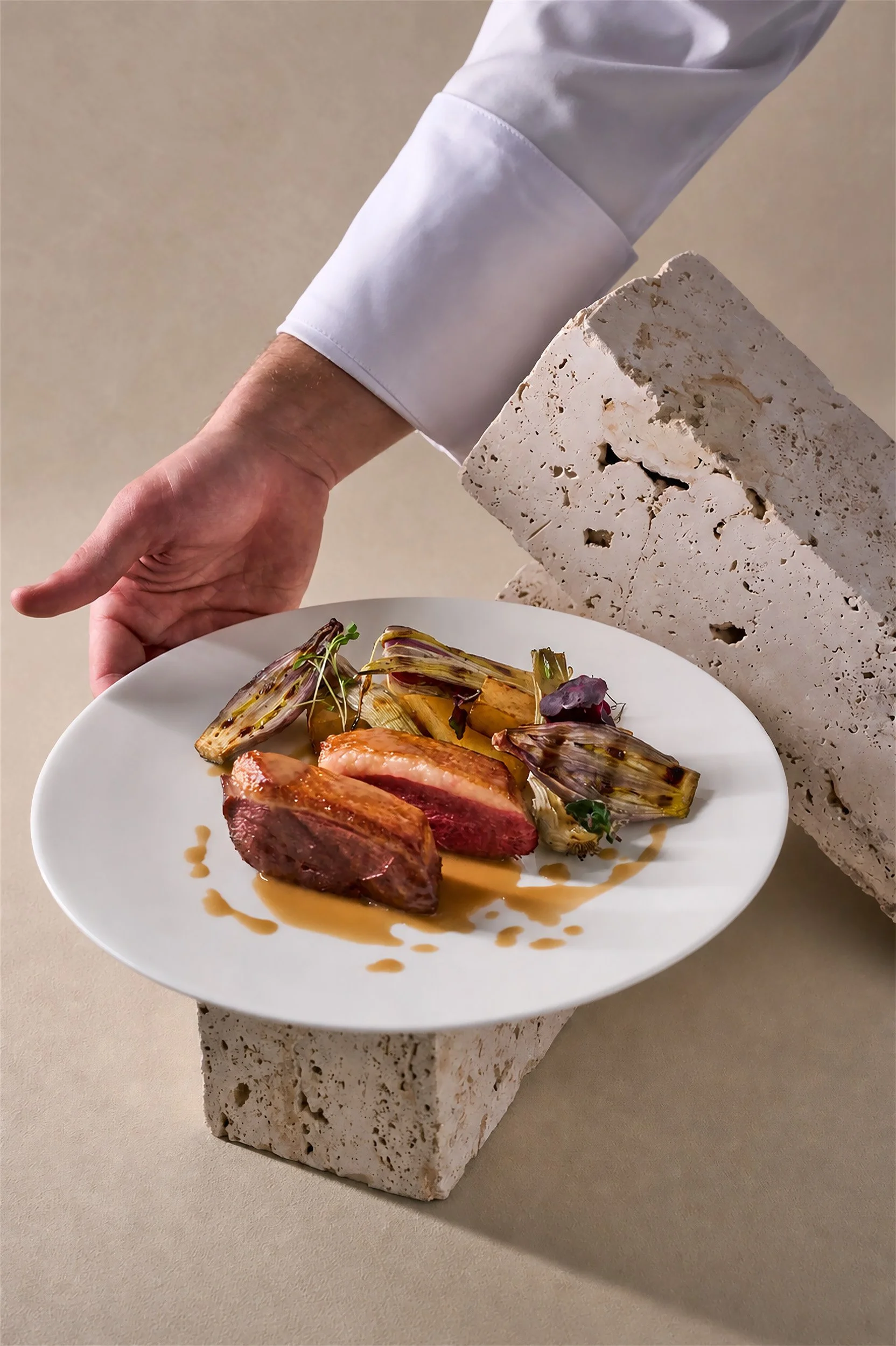 Fotografia food professionale dall'alto: chef presenta piatto di anatra con cipolle grigliate e jus in ristorante a Milano — Cardinali Studio