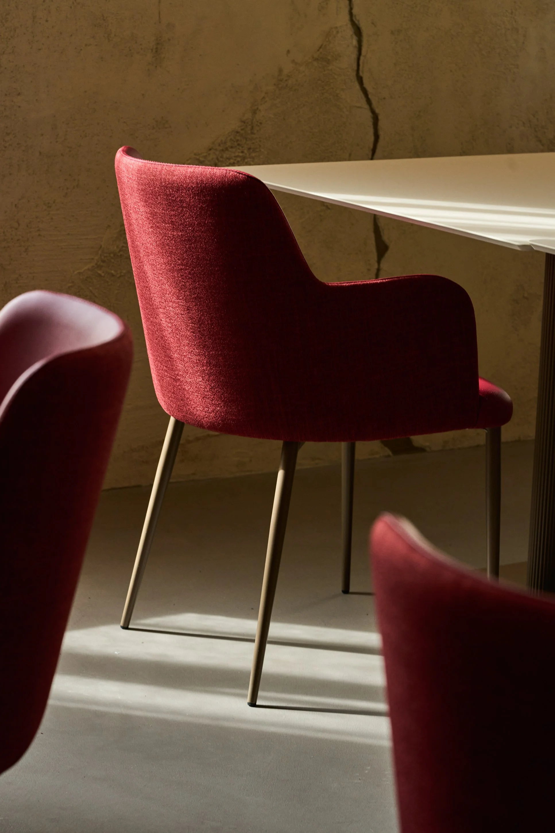 Fotografia d'interni sala ristorante di design a Milano: sedie in velluto bordeaux e tavolo bianco con luce naturale — Cardinali Studio