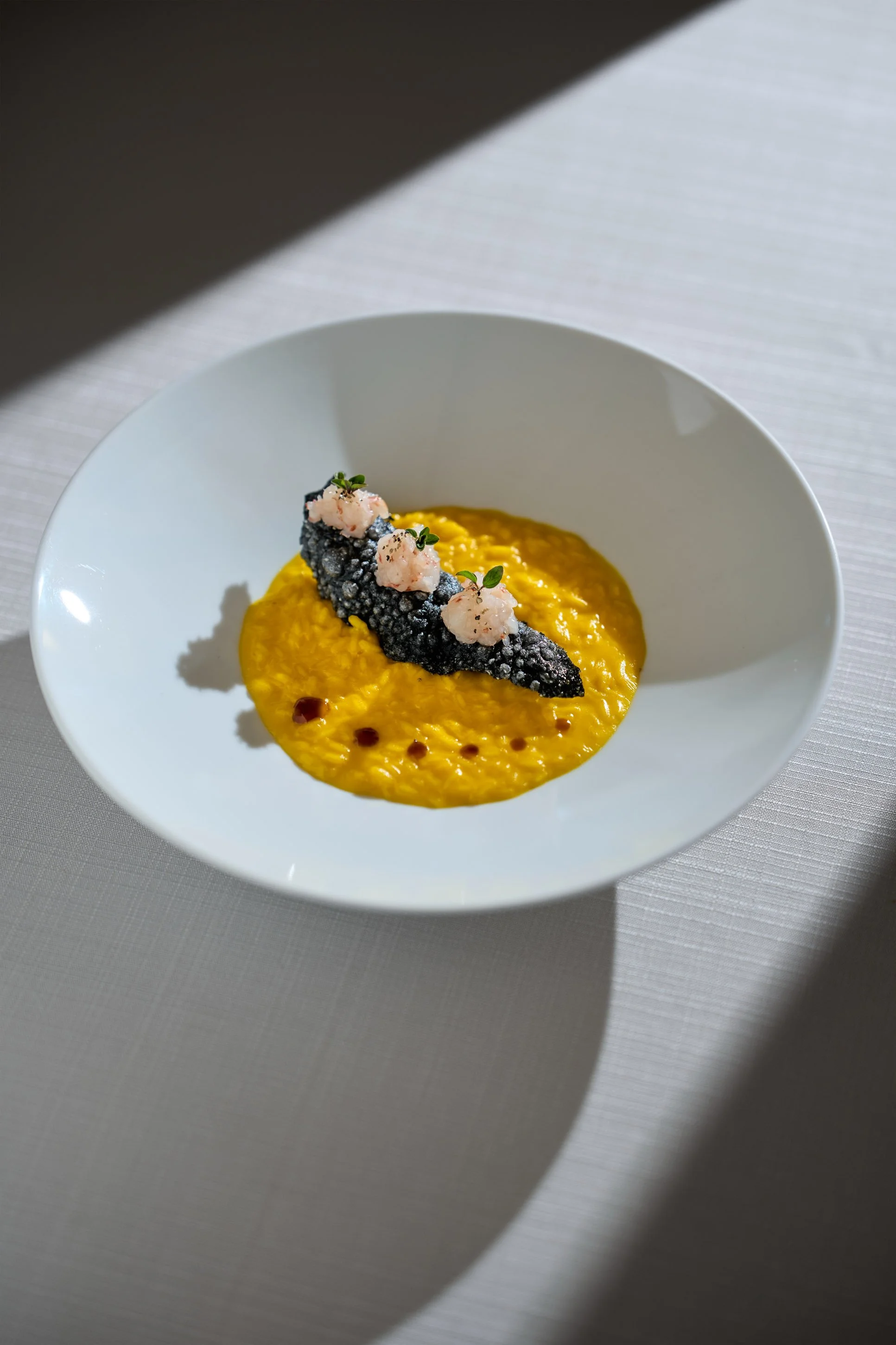 Fotografia food professionale di risotto allo zafferano con nero di seppia e gamberi, ristorante gourmet a Milano — Cardinali Studio