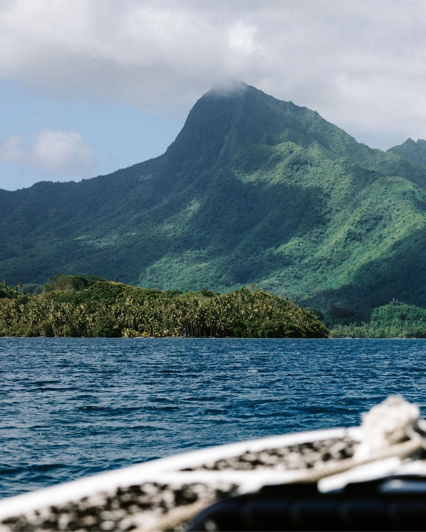 Sailing toward her, you feel the weight of centuries resting in green folds and shadowed cliffs. The mountain does not move, yet she speaks, a silent hymn of resilience, guarding the island with every breath of wind and wave.

Photo credit : @tinihau