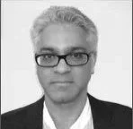 Black and white portrait of a man with glasses, short gray hair, wearing a suit and tie.