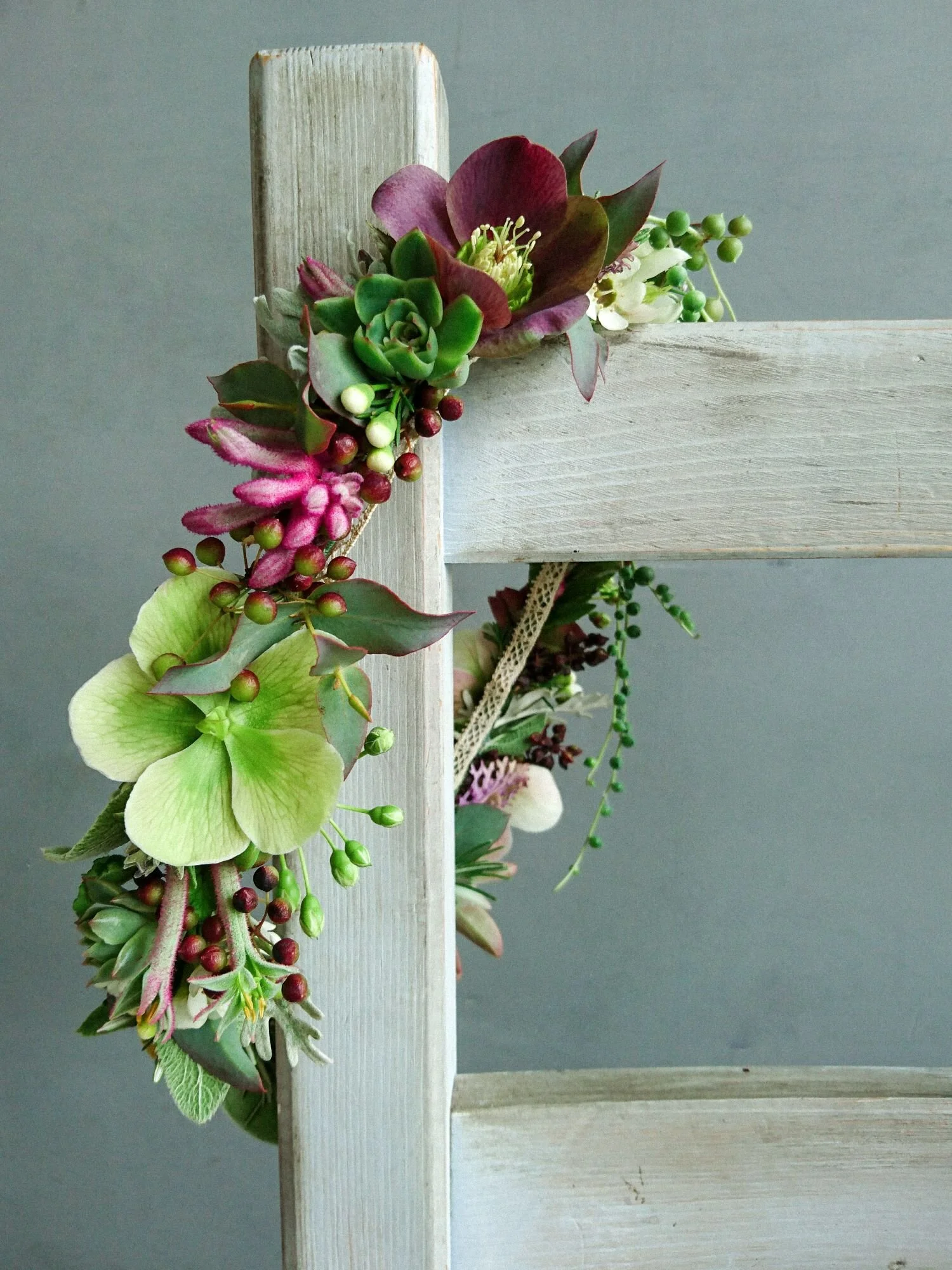 Coroncina di fiori boho chic con ellebori, piante grasse e altri fiori di marzo