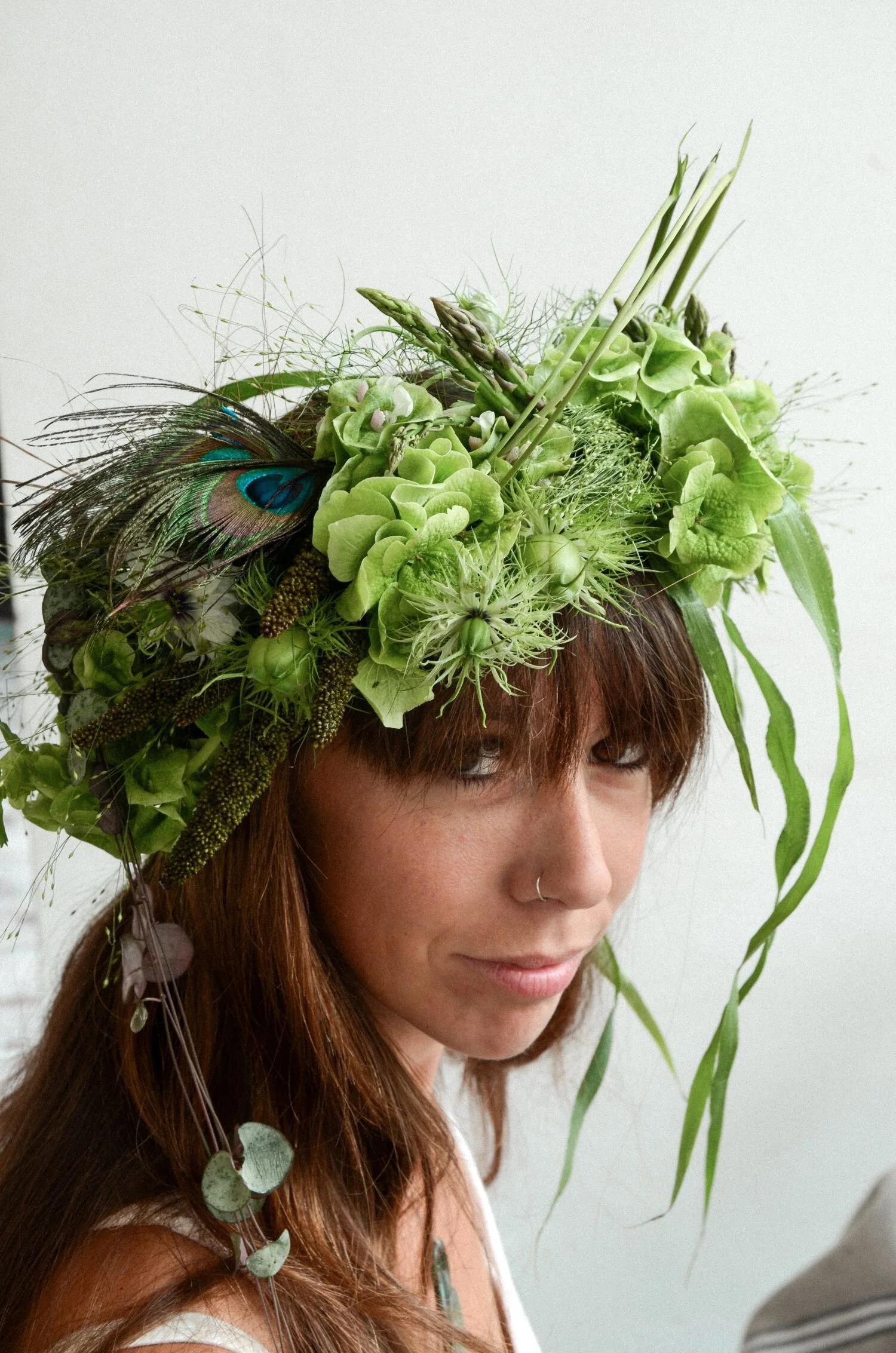 Coroncina di fiori verdi estive, con piuma di pavone.