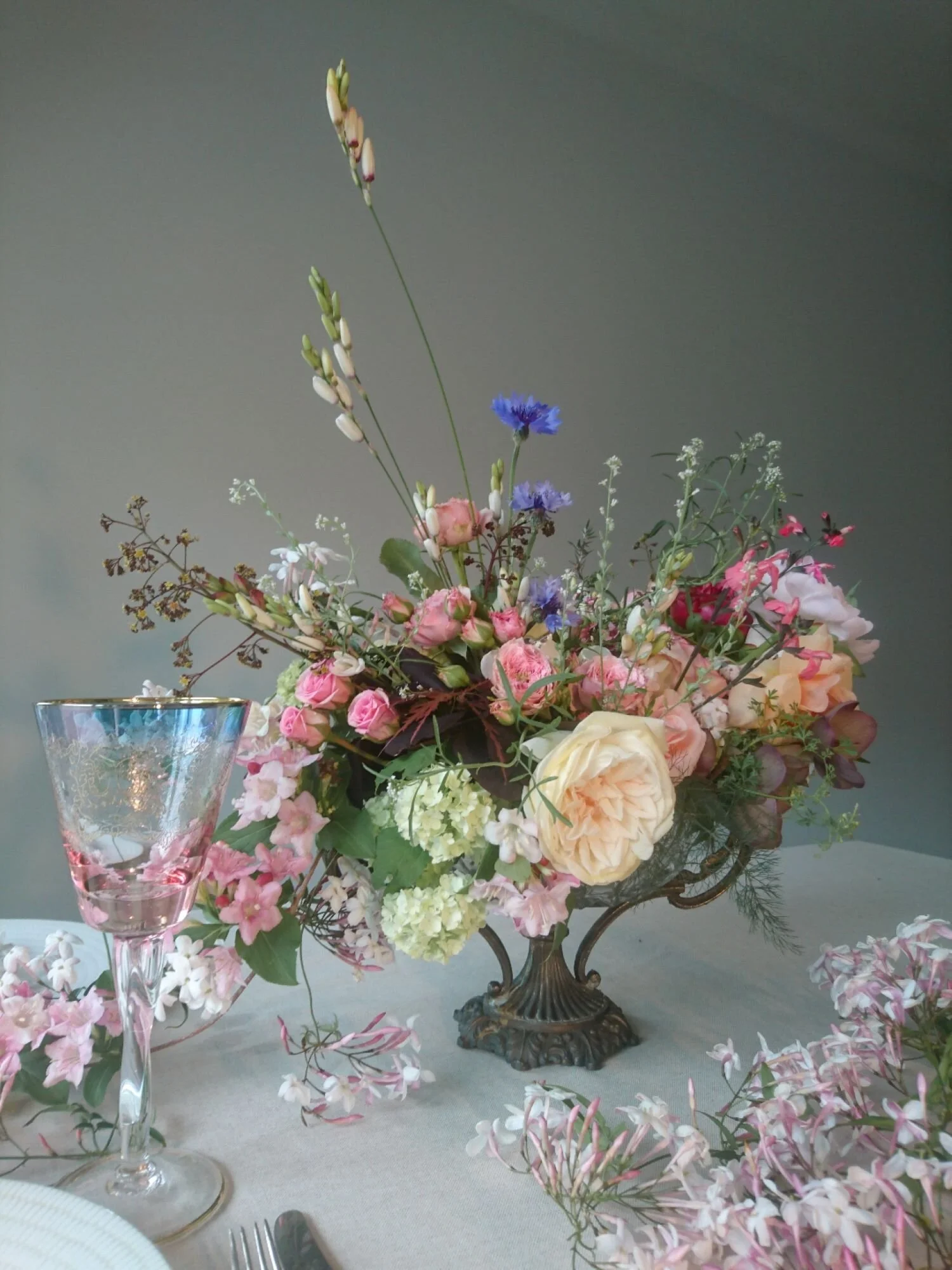 Mid spring compote arrangement of garden grown flowers including roses and jasmine