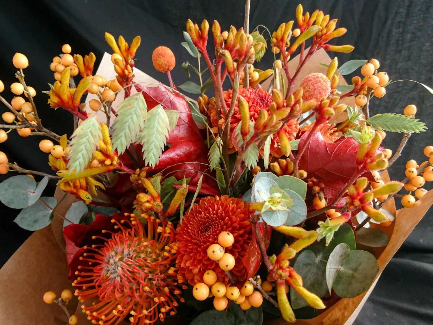 Orange bouquet of proteas, berries, kangaroo paw and other autumn flowers. Bouquet di bacche arancione, protea, zampa di canguro (anigozanthus) e altri fiori autunnali.