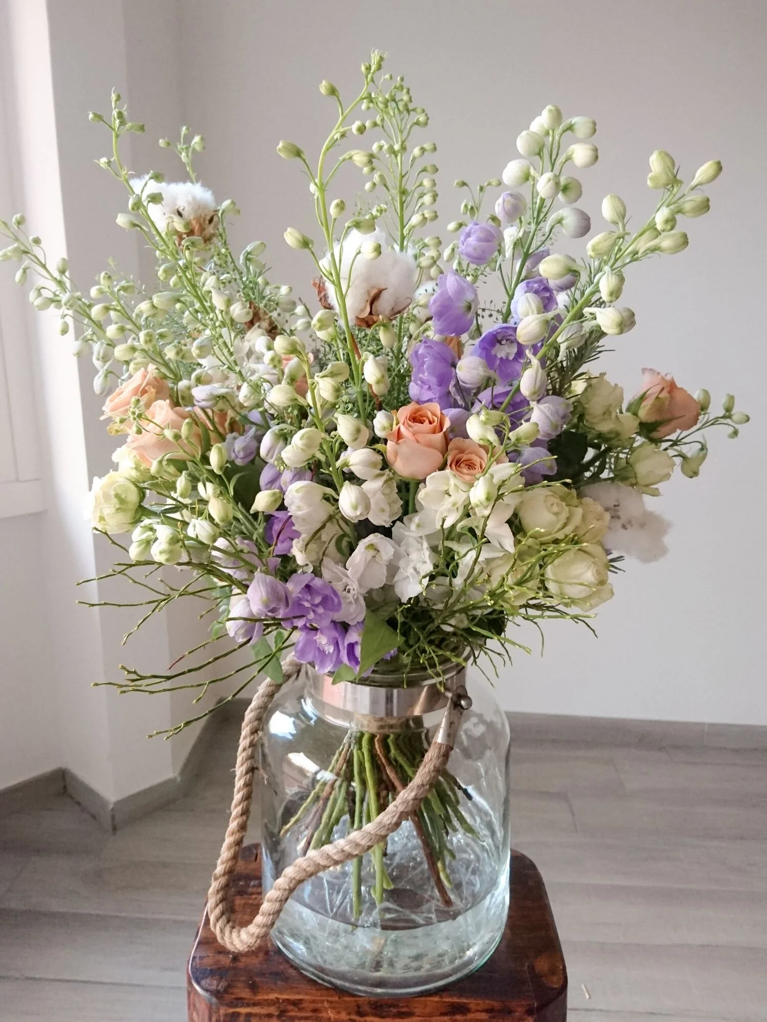 Bouquet of autumn flowering delphiniums and cappuccino roses in a glass vase. Bouquet di delfinium blu e rose cappuccino in un vaso di vetro. 