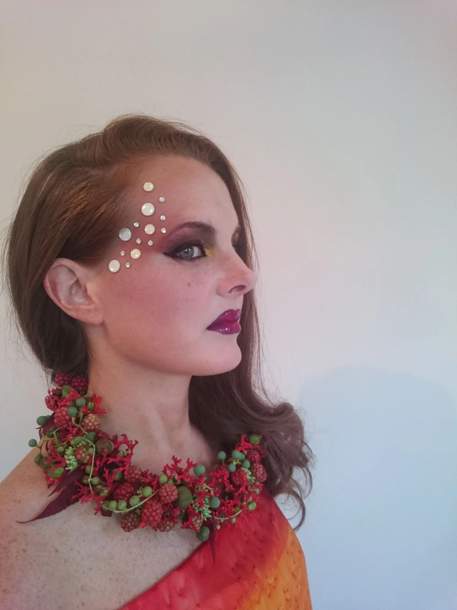 Modella con collana di fiori freschi. Trucco per servizio fotografico. Fatta con jatropha, lamponi, e bacche verdi. Perfetto per una sposa al matrimonio. Accessori floreali insoliti