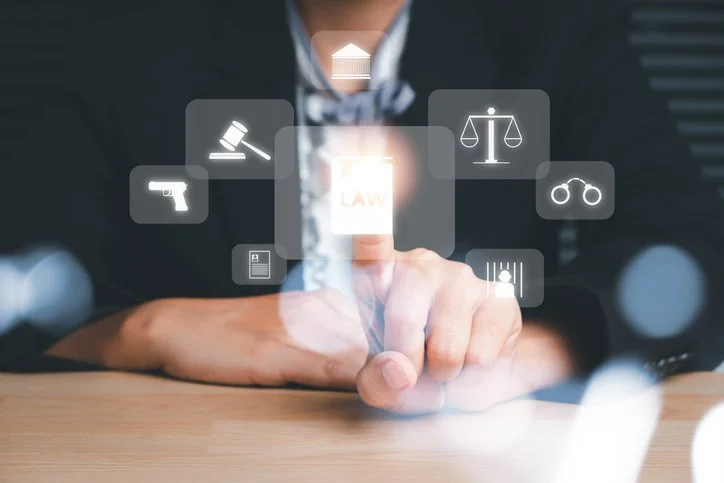 Person in business suit touching a transparent digital interface with icons representing law, justice scales, handcuffs, gun, courthouse, and legal documents.