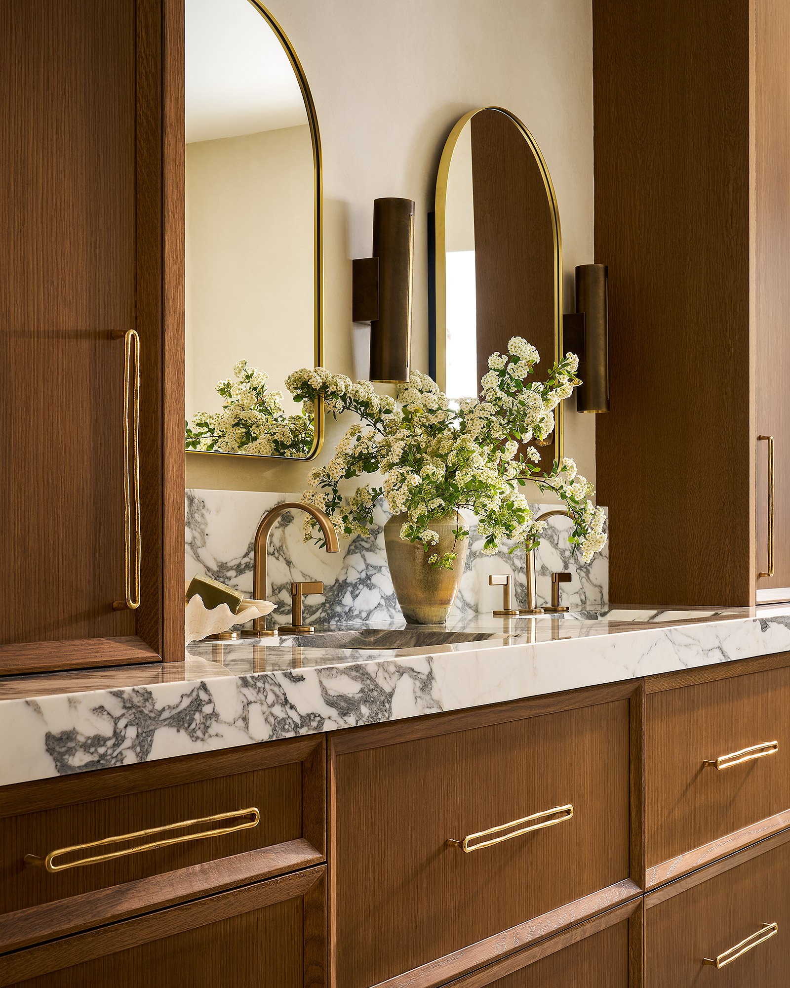 Luxury bathroom with custom wood vanity, double sinks, marble countertop, and tadelakt plaster walls, angled view.