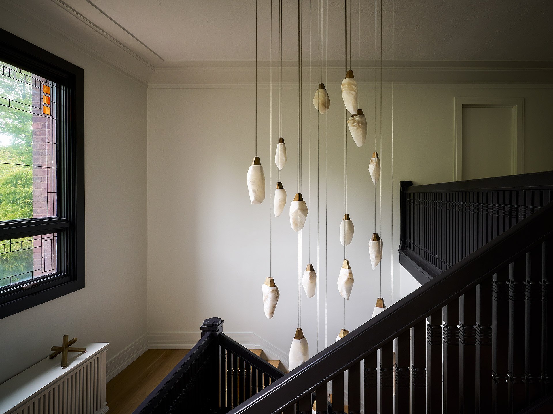 Custom staircase with alabaster drop pendant lighting in luxury foyer.