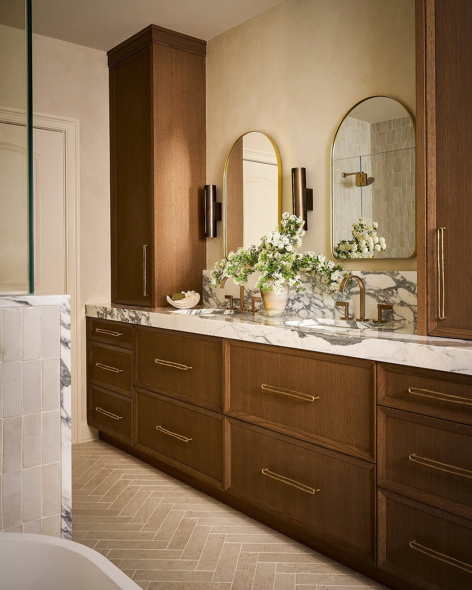 Luxury bathroom with custom wood vanity, double sinks, marble countertop, and tadelakt plaster walls, angled view.