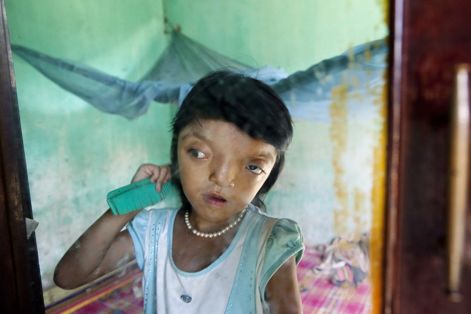 LOOKING IN THE MIRROR, IT IS UNCLEAR HOW LY REGARDS HERSELF. SHE TAKES CARE WITH HER APPEARANCE, WEARING THE SAME PLASTIC PEARL NECKLACE EACH DAY, 2010