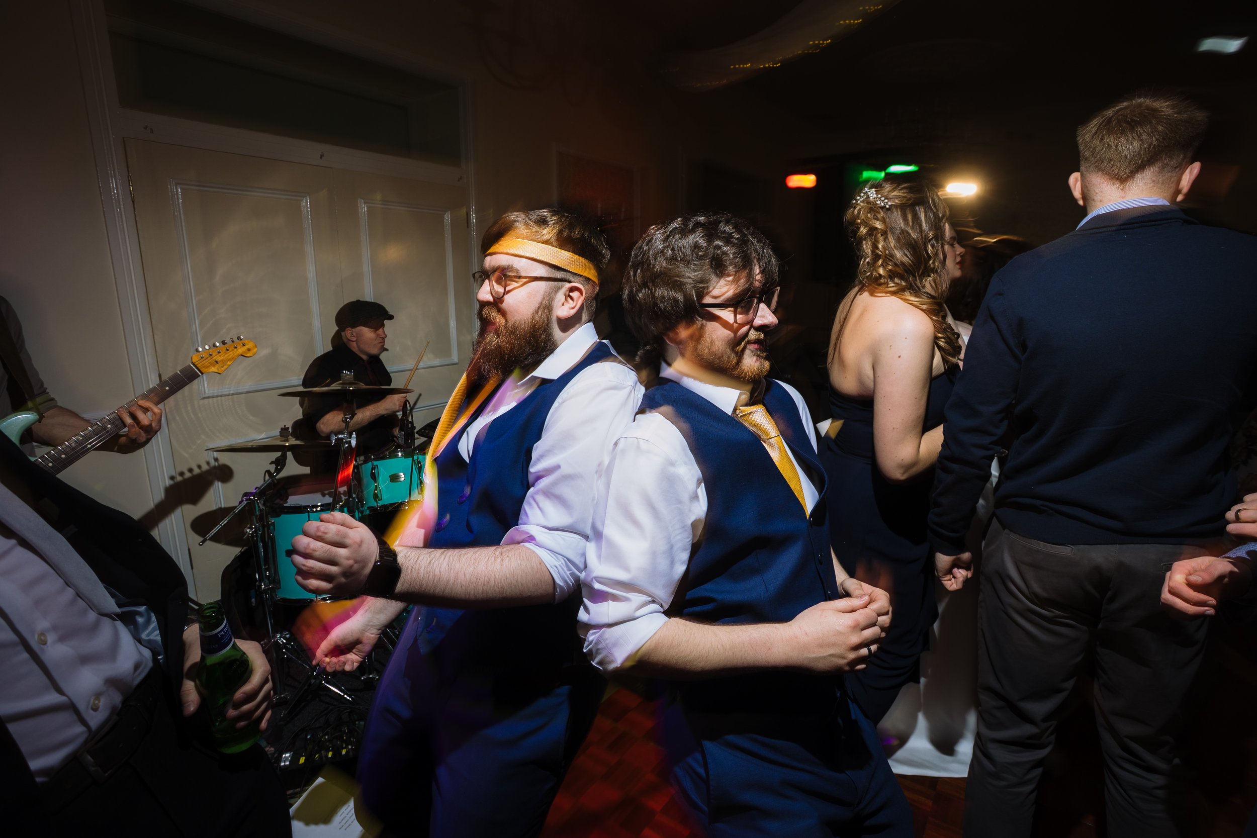 People dancing at a party, with a live band playing in the background.