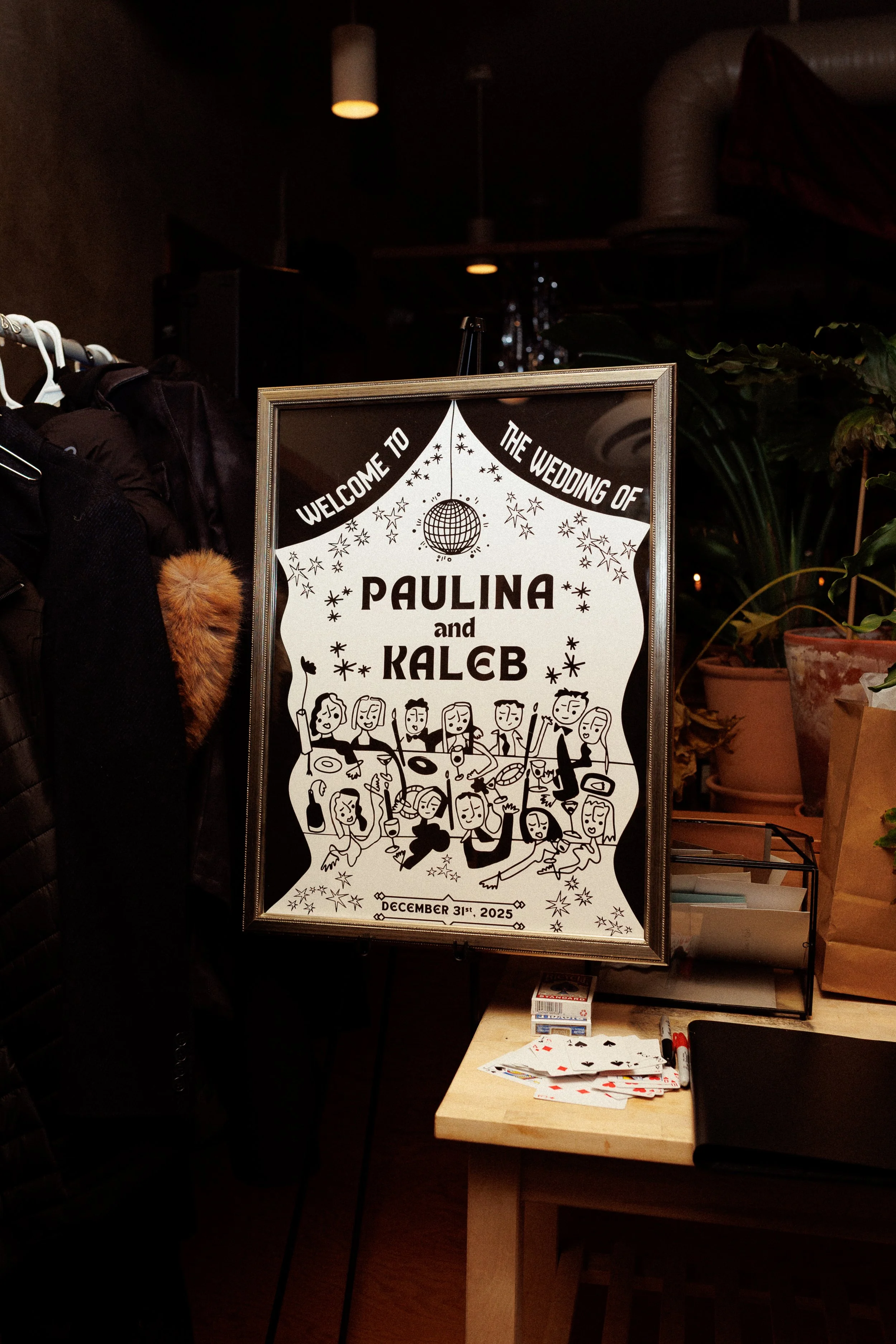A wedding sign for Paulina and Kaleb with cartoon illustrations of guests playing guitar and singing, decorated with stars and a disco ball at the top, dated December 31st, 2025.