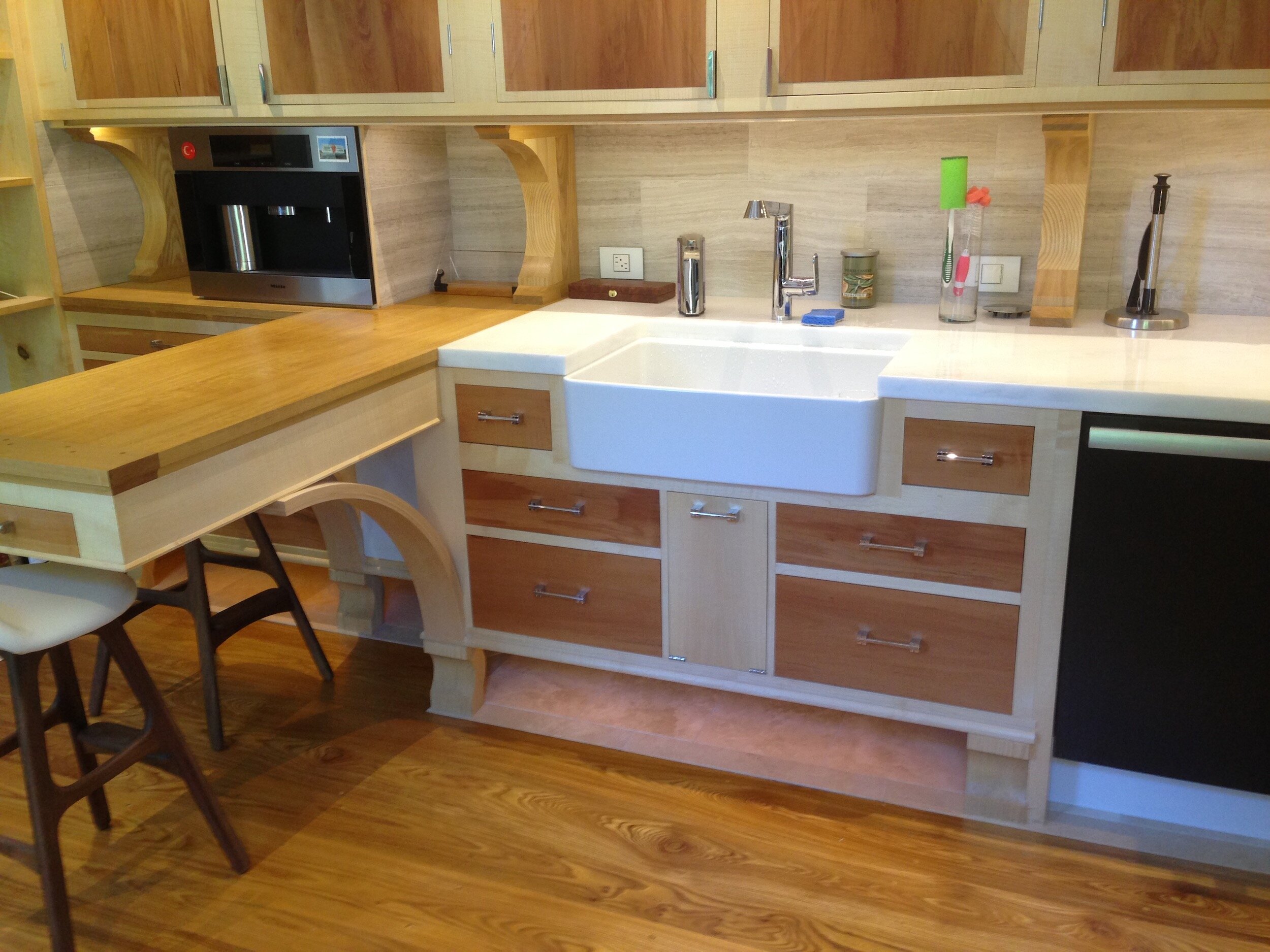 Cabinets in English scyamore and Swiss pear float above a sloped limestone tile surface ( resisting the accumulation of debris) which abuts the Red Elm wide plank floor. hidden lighting glows down from the upper cabinets and lower. An all-drawer co