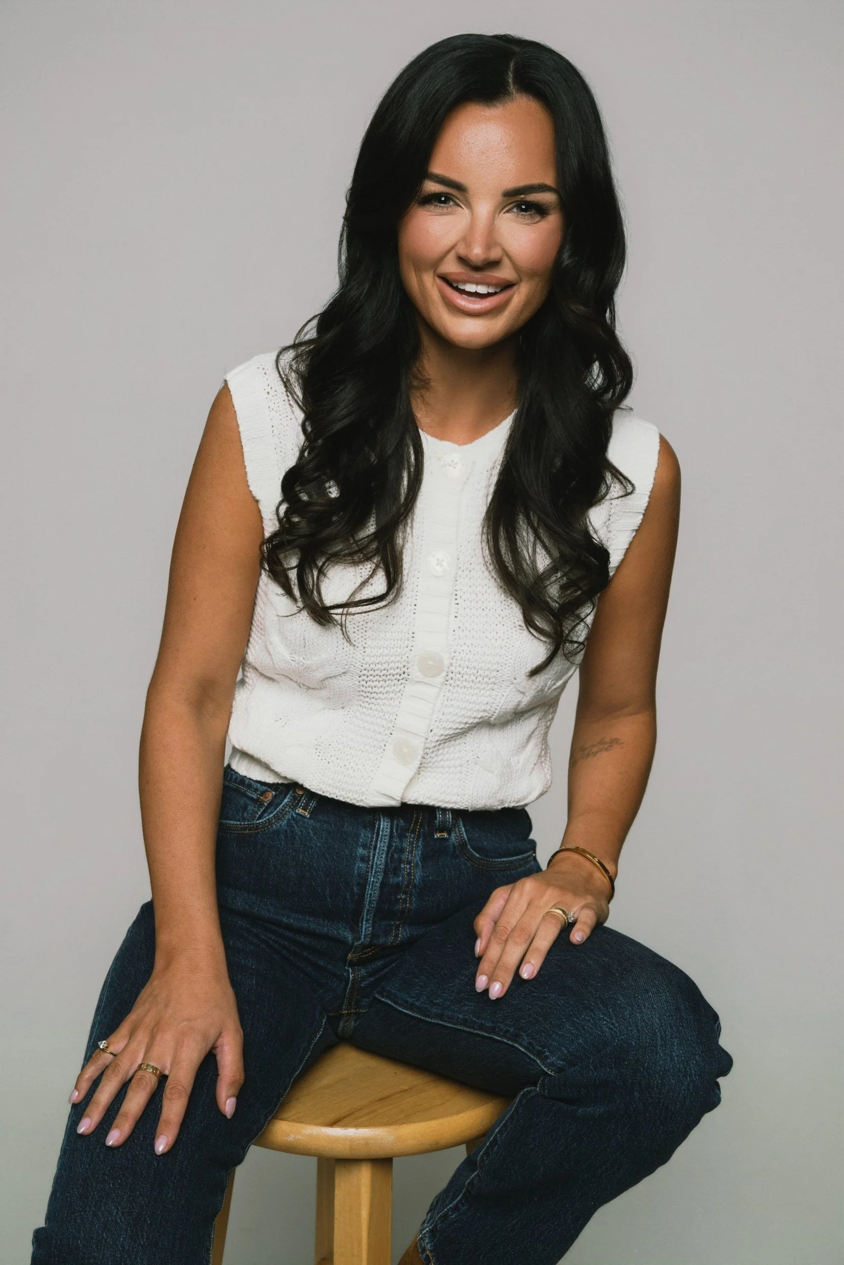 Smiling branding portrait on wooden stool at Lightbox OKC photo studio in Oklahoma CityProfessional headshot in white turtleneck on gray seamless at Lightbox OKC, Oklahoma City headshot studio