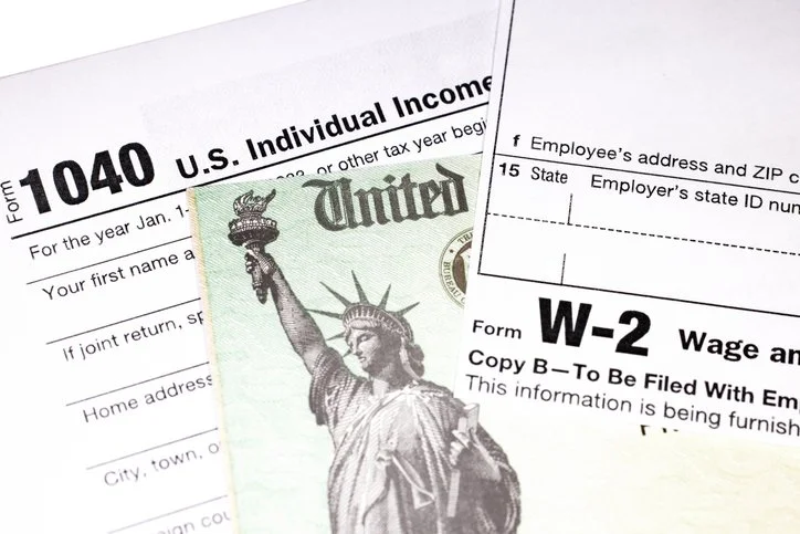 US Tax Forms W-2, 1040, and a refund check spread out next to each other