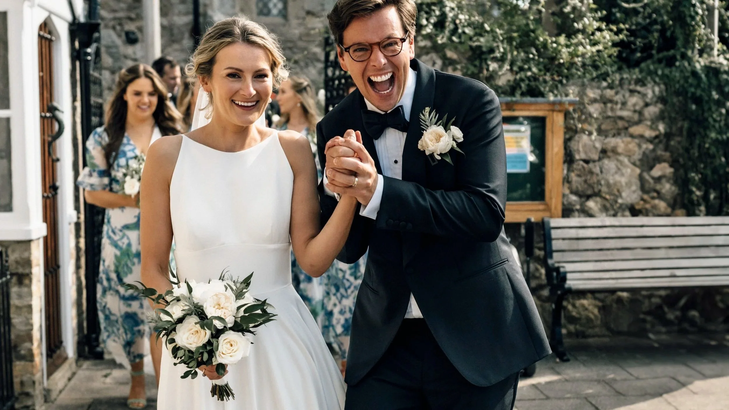 A happy bride and groom celebrating their wedding outdoors, with bridesmaids in the background. In Yarmouth on the Isle of Wight. Wedding bouquet flowers by wed & prosper