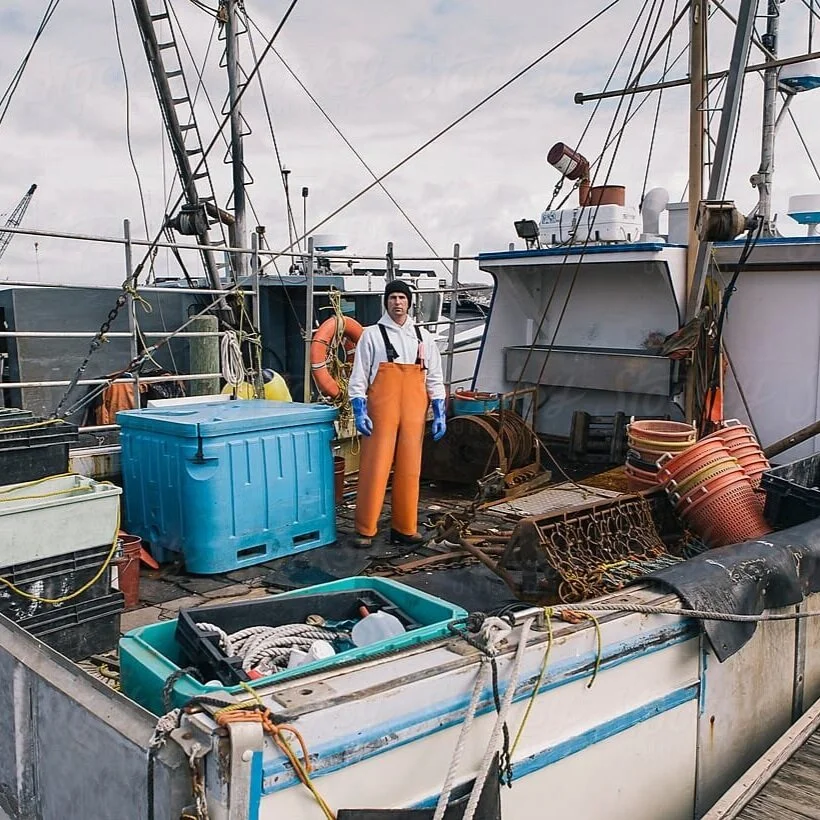 A fisherman stands on the deck of a commercial fishing boat