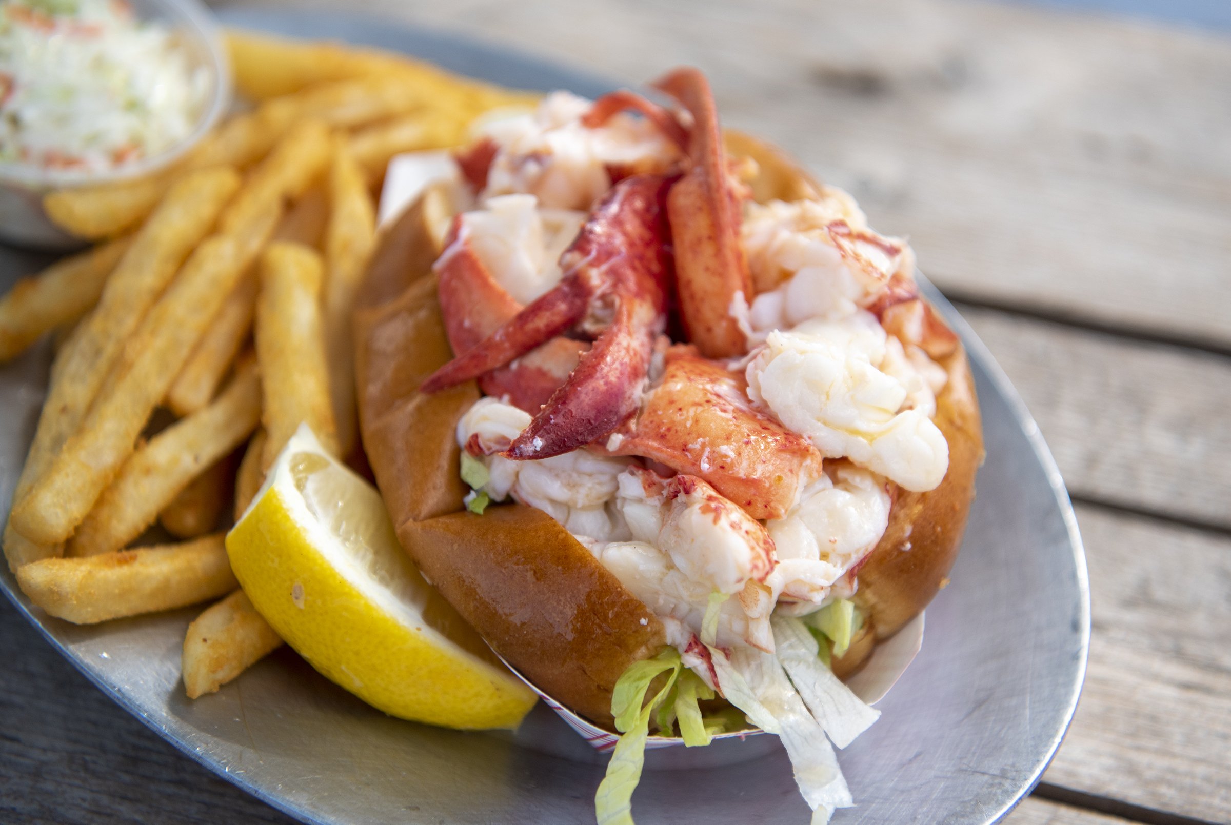 Lobster Roll from Chatham Pier Fish Market plated with French fries ready to be enjoyed.