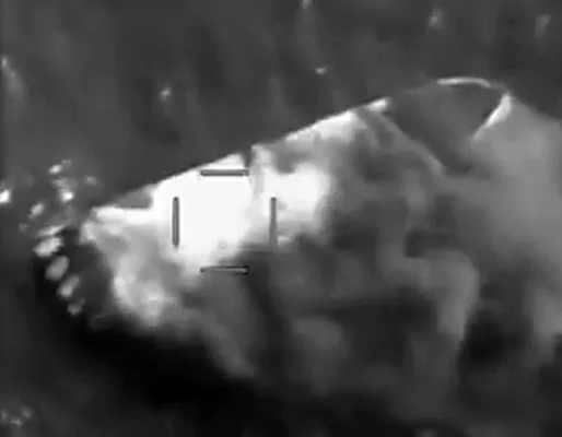 Grainy B&W photograph of a burning boat from a military targeting system