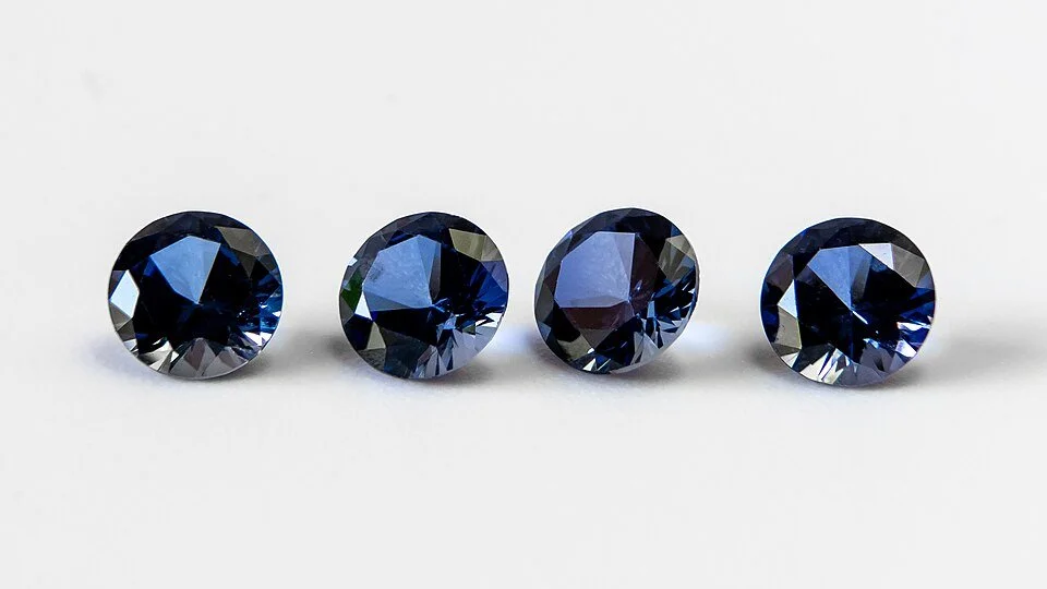Photo of four, blue, faceted gemstones