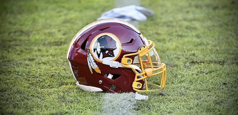 Photo of a maroon football helmet sitting on a football field that bears a profile image of a Native American man