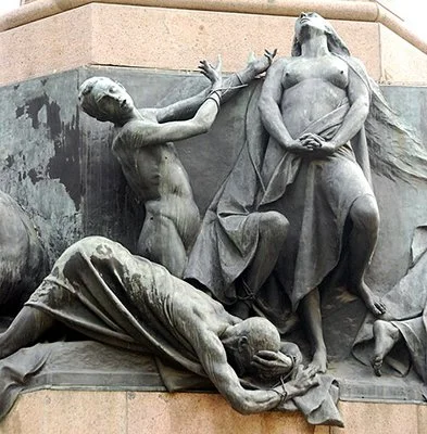 Statue detail of 3 figures: a woman looking up; a man with bound hands raised & looking away; & a prone man, head in hands