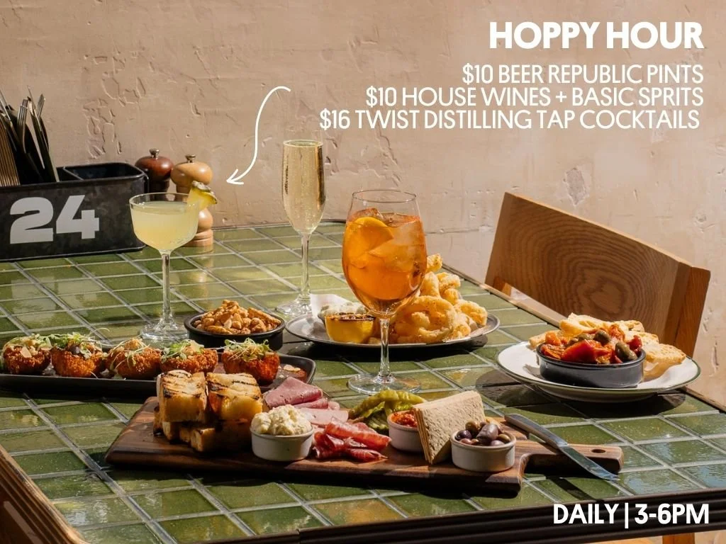 Table with drinks and appetizers displaying 'Hoppy Hour' specials, including beer, wines, and cocktails, daily from 3-6 PM.