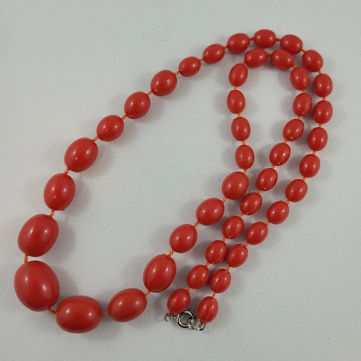 Early Moulded Plastic Cherry Red Fixed Oval Bead Graduated 24 Inch Matinee Necklace.jpg