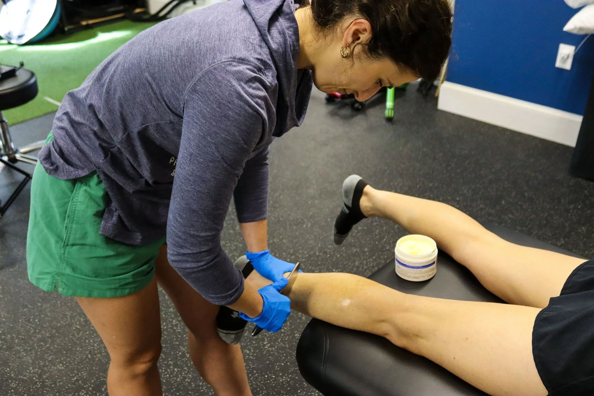 a woman performing a manual therapy technique on a persons calf as they lay face down on a table