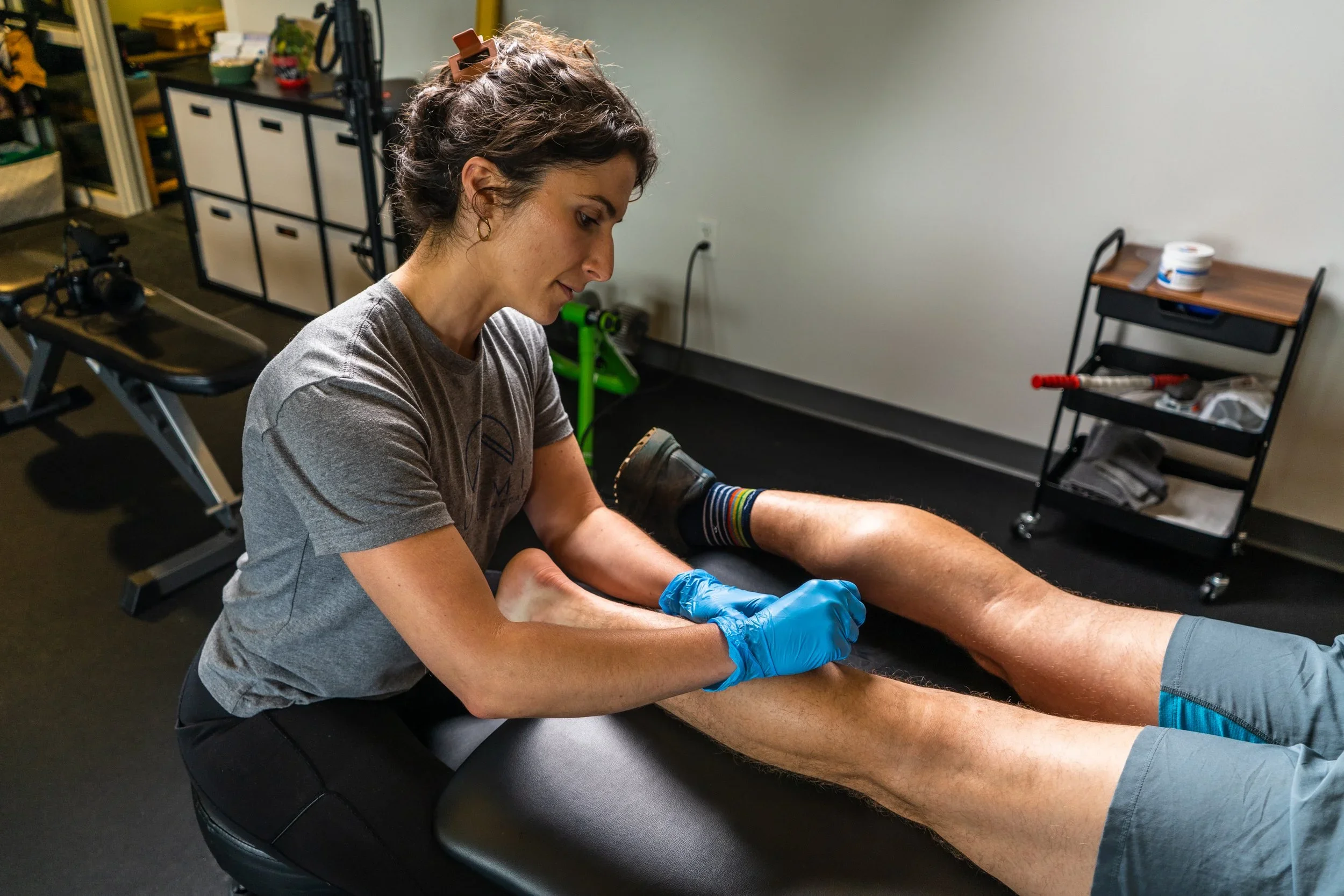 a woman performing a dry needling treatment on a calf