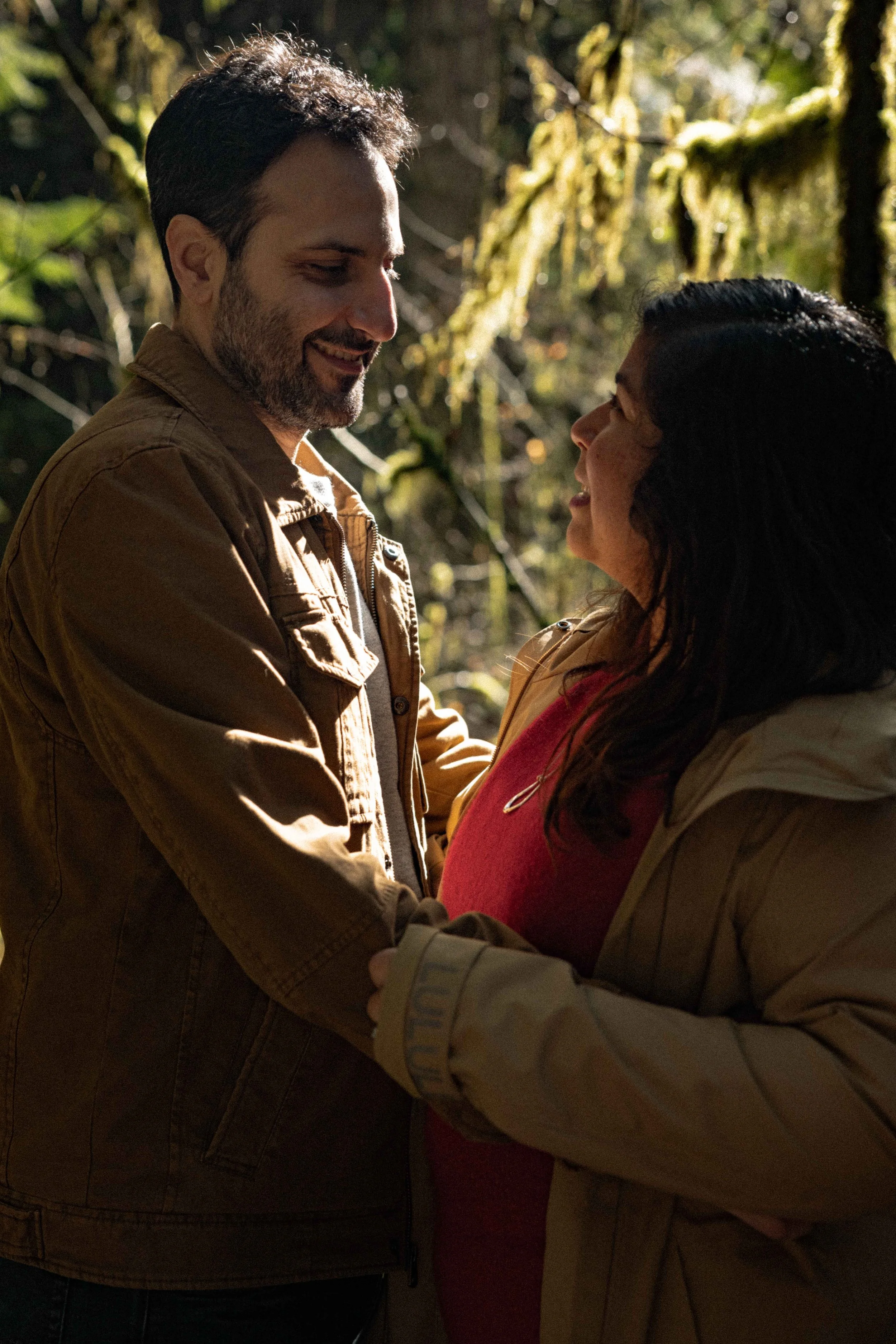 newly engaged couple holds each other in a mossy forest.