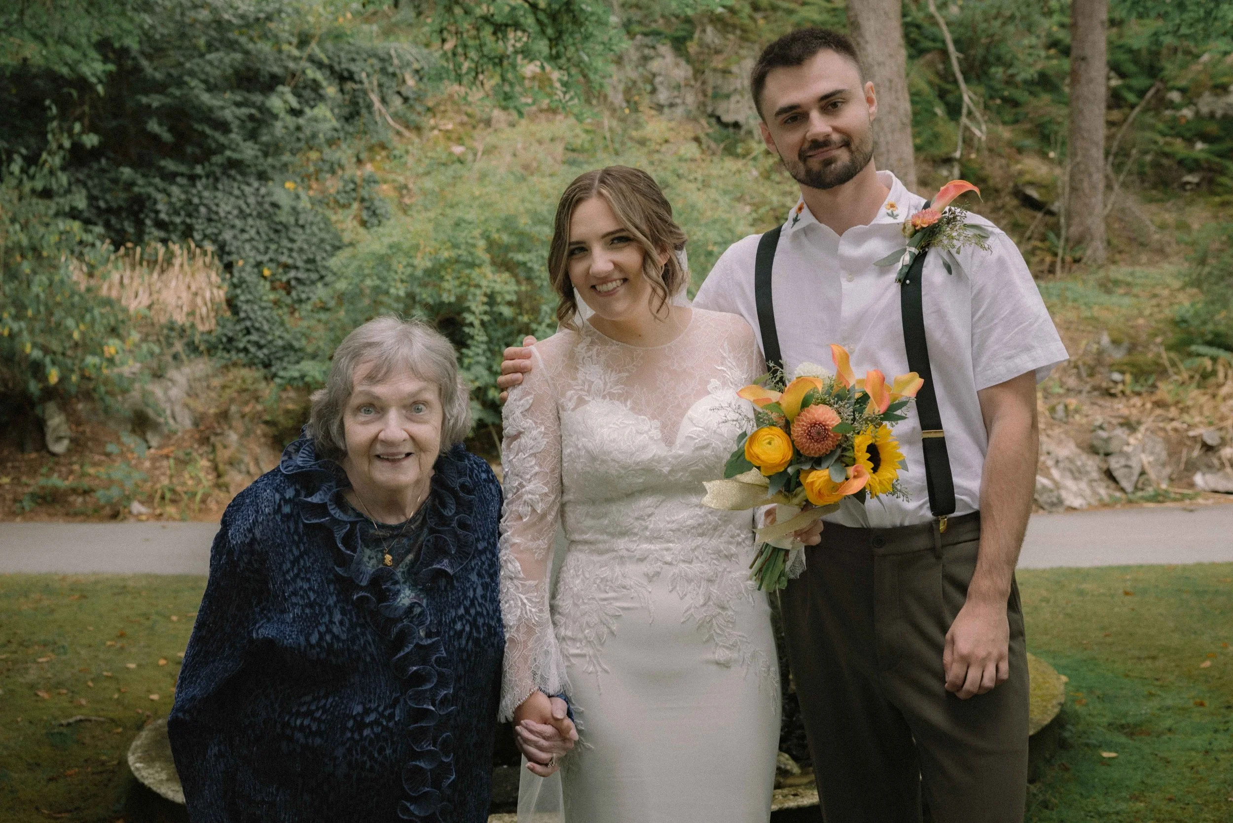 A bride holding hands with her grandmother holding a sunflower bouquet at Minnekhada Regional Park