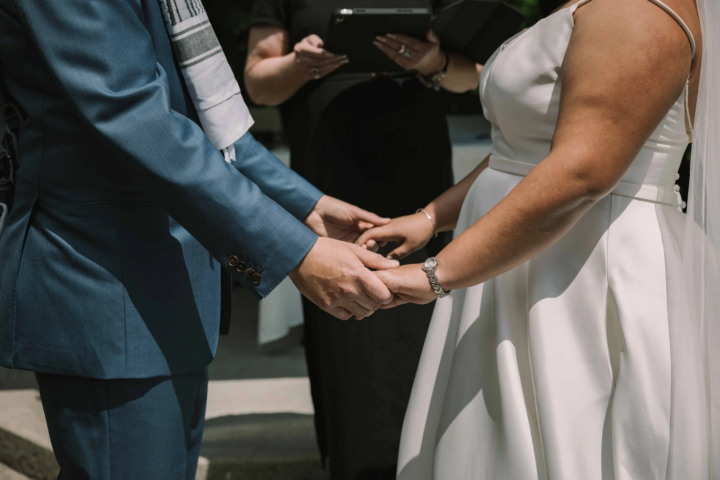 A couple hold hands at the alter on their wedding day, close up of the hands.