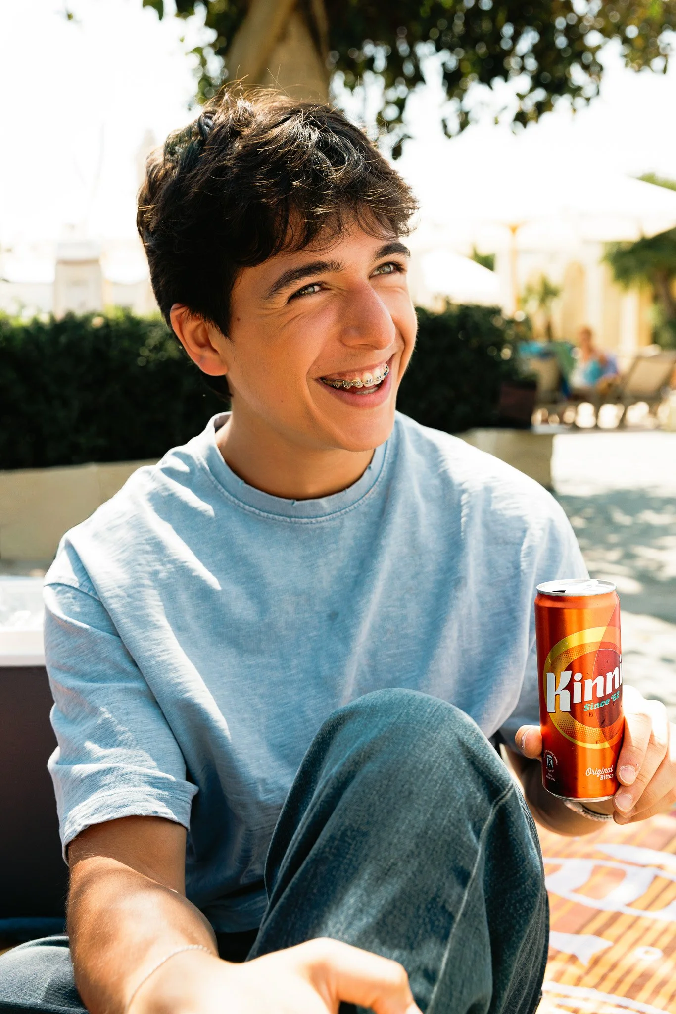 guy holding a kinnie can outdoors, smiling, springtime 