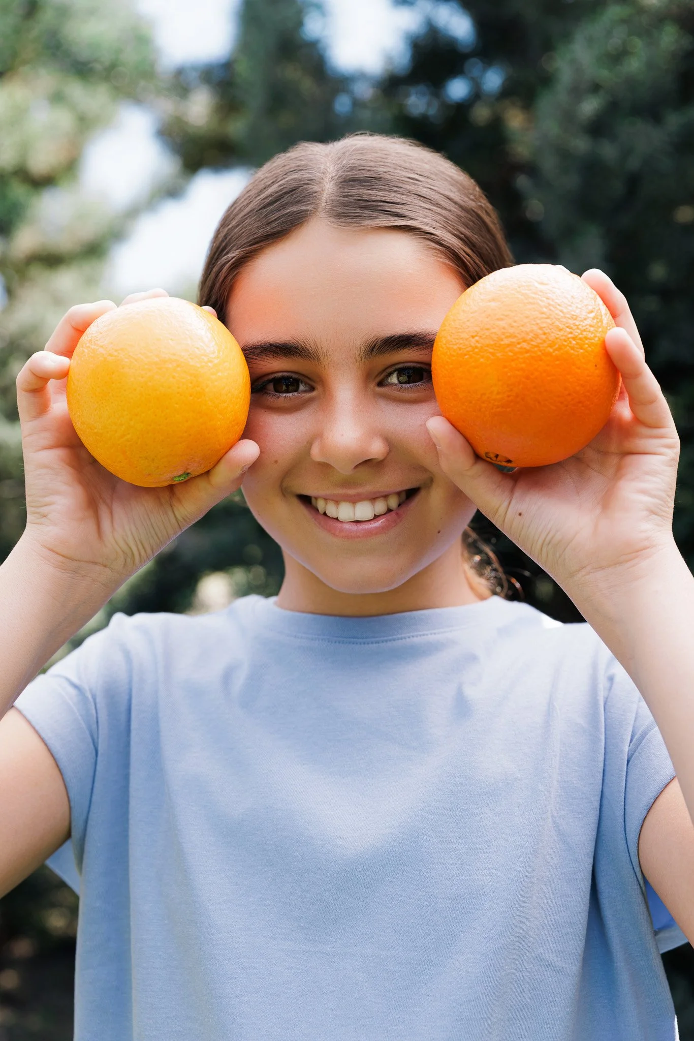 young girl holding two oranges, commercial photoshoot for safari juices