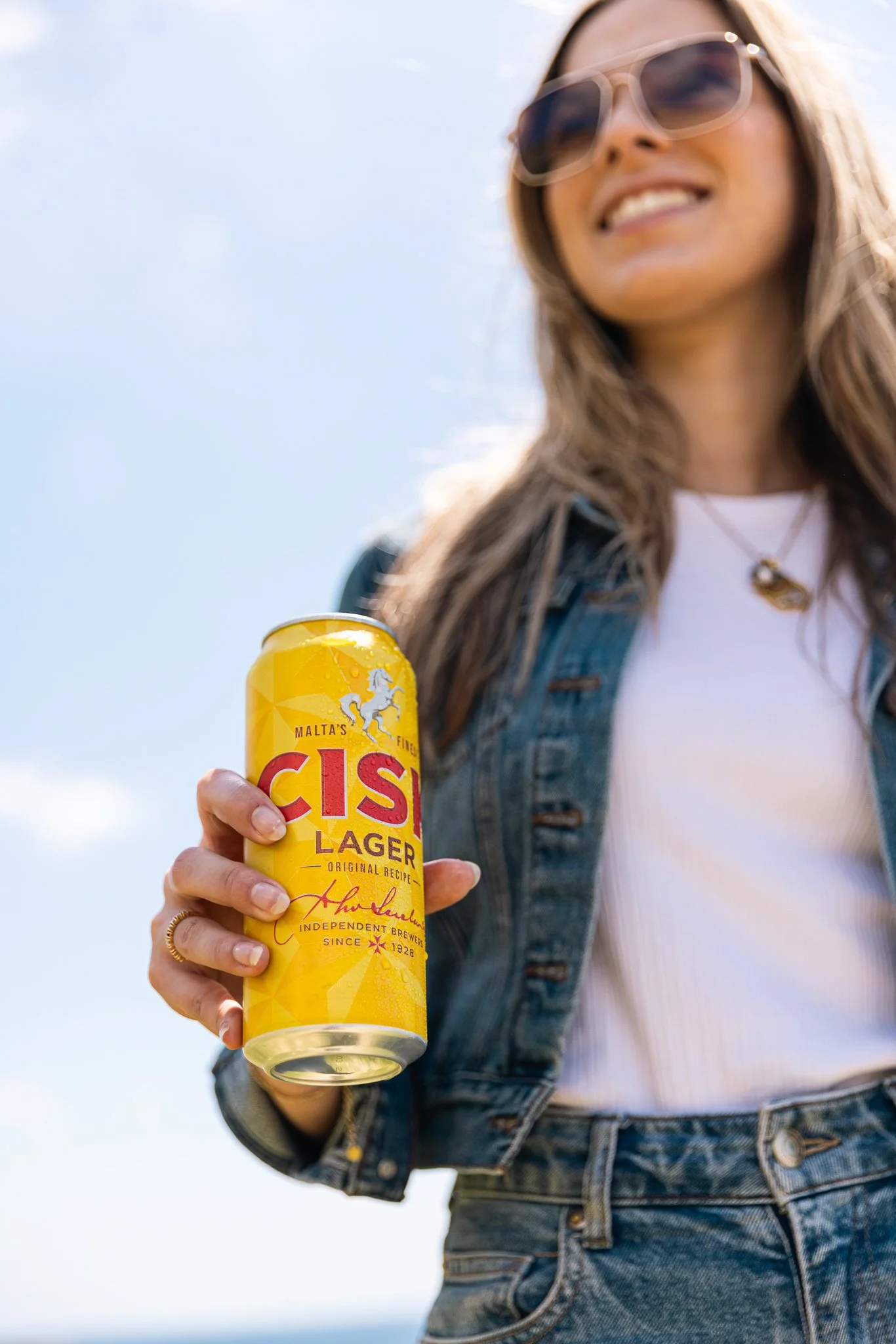 woman holding a cisk lager outdoors, springtime, shoot