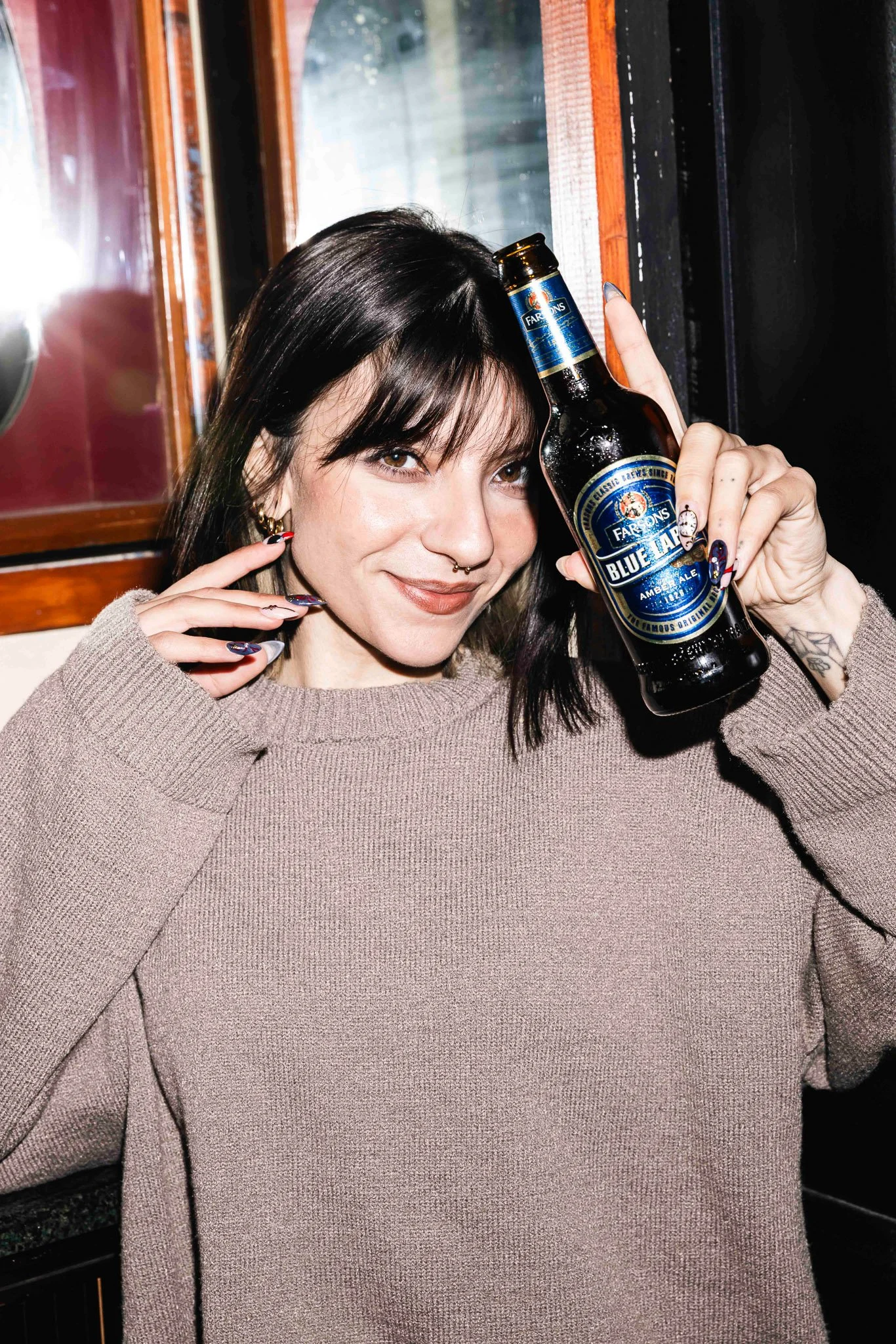 woman smiling holding classic brews blue label bottle in hand, photoshoot