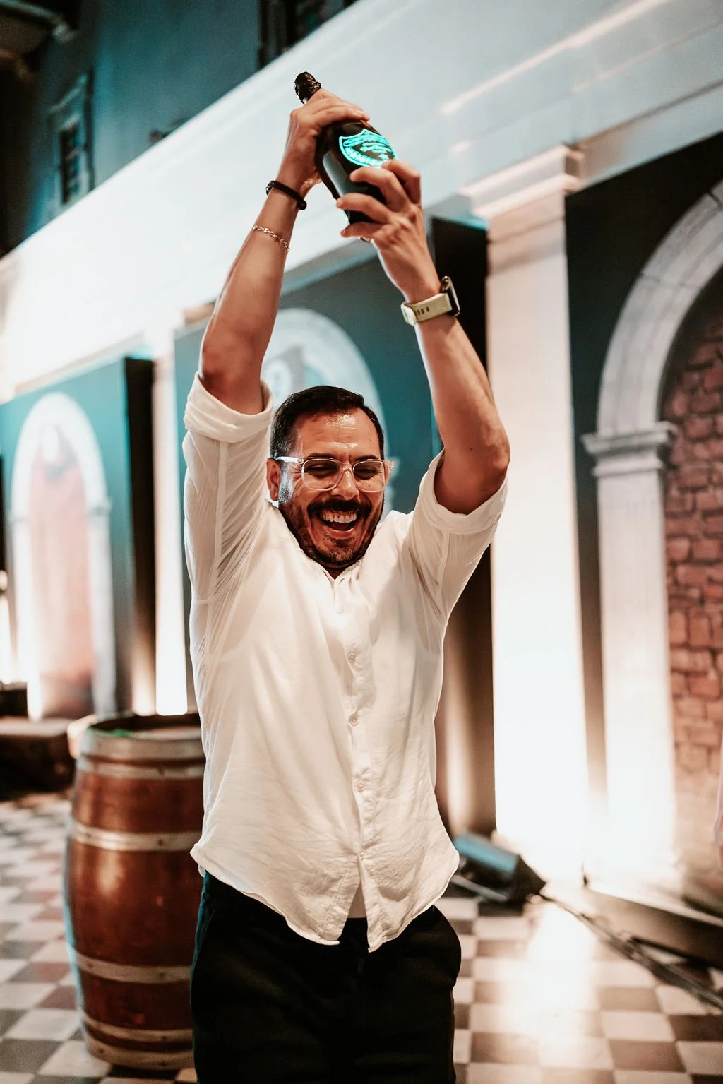 man celebrating, holding up a wine bottle, event photography