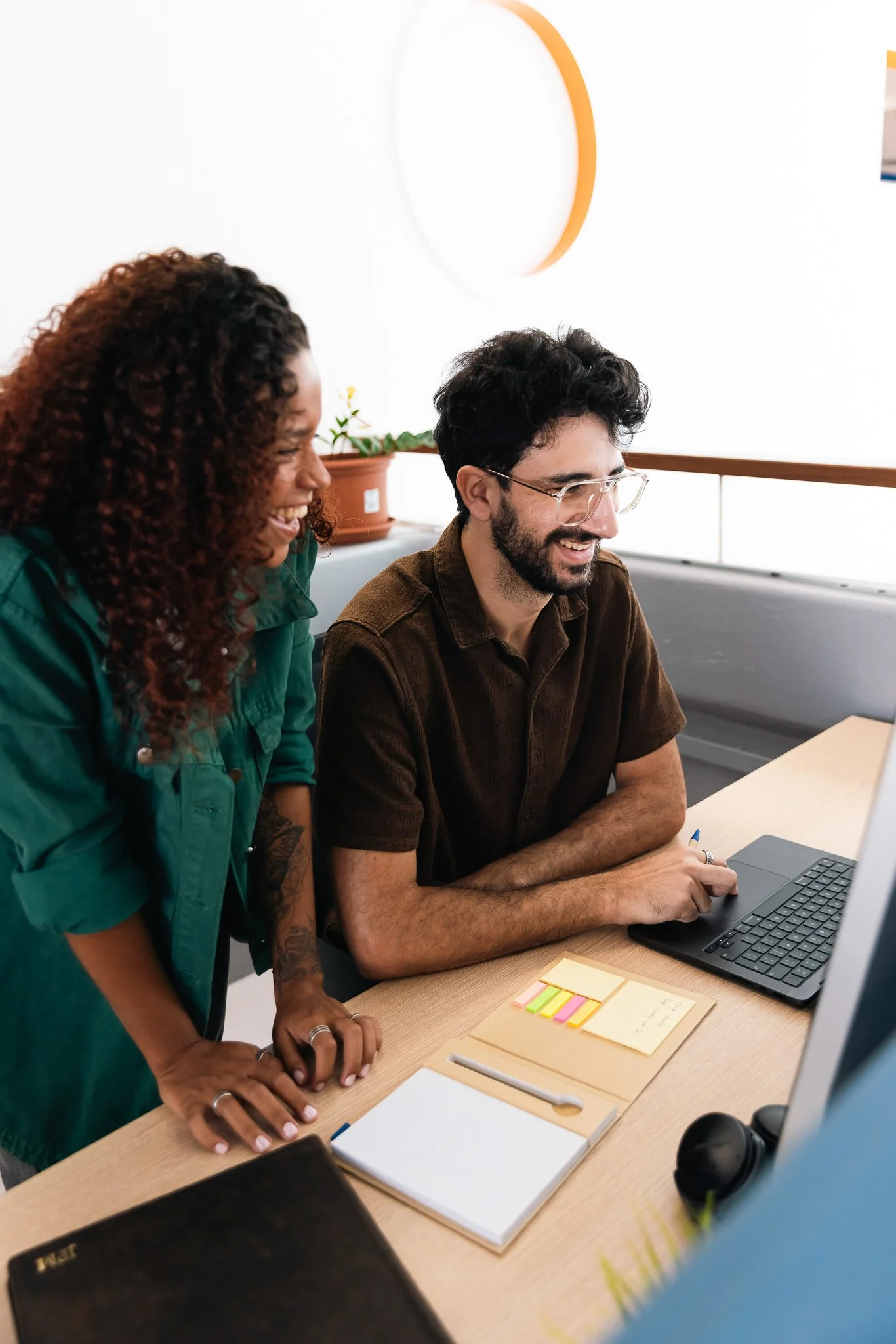 two people at a desk looking at the laptop, smiling, coworking