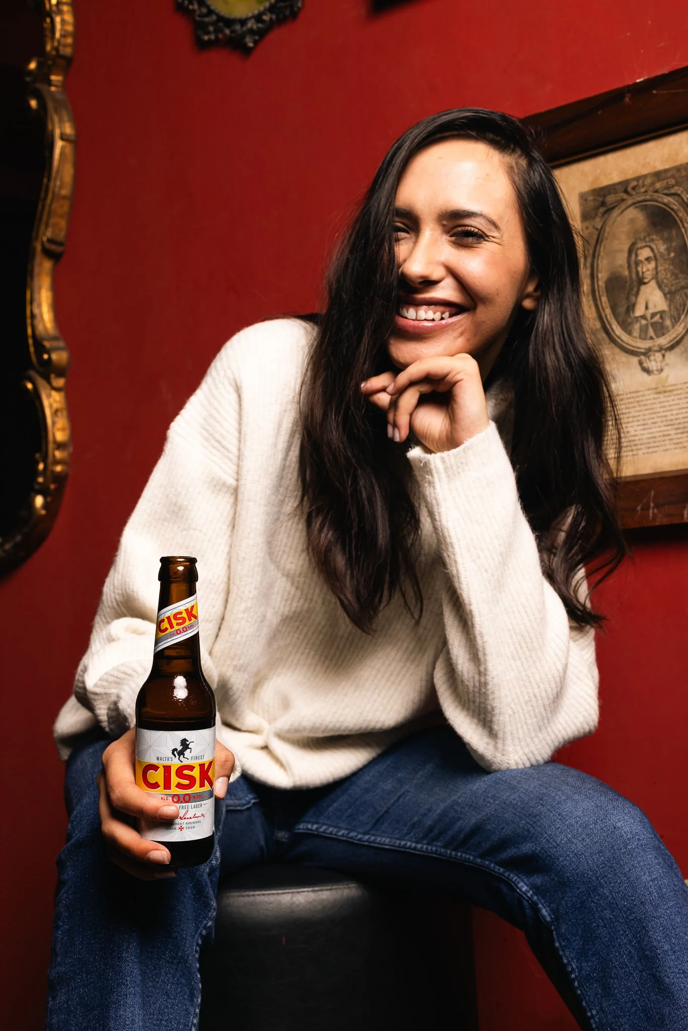 woman smiling, with a cisk 0.0 bottle in hand, winter photoshoot
