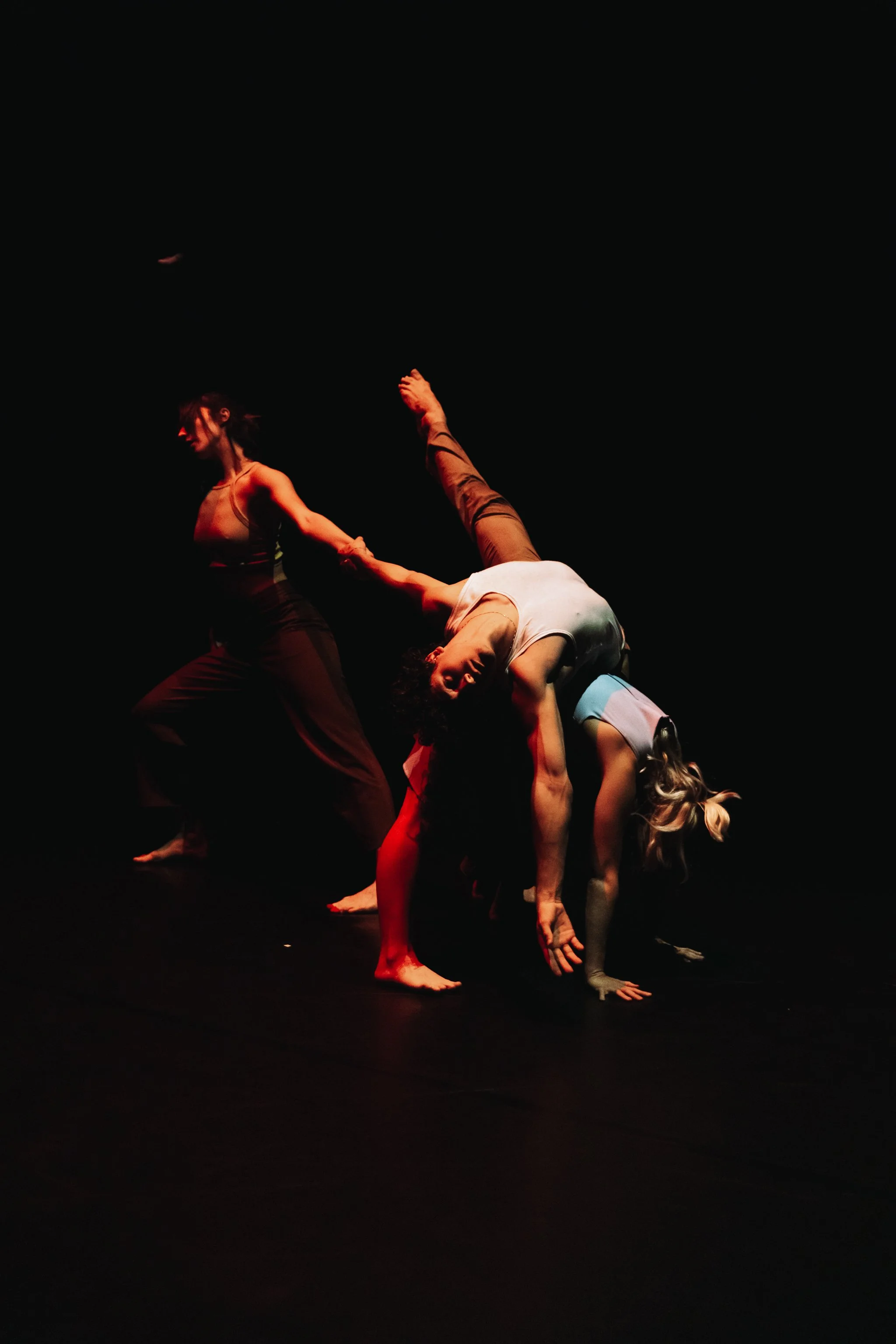 three dancers on stage, moody lighting, dance photography.